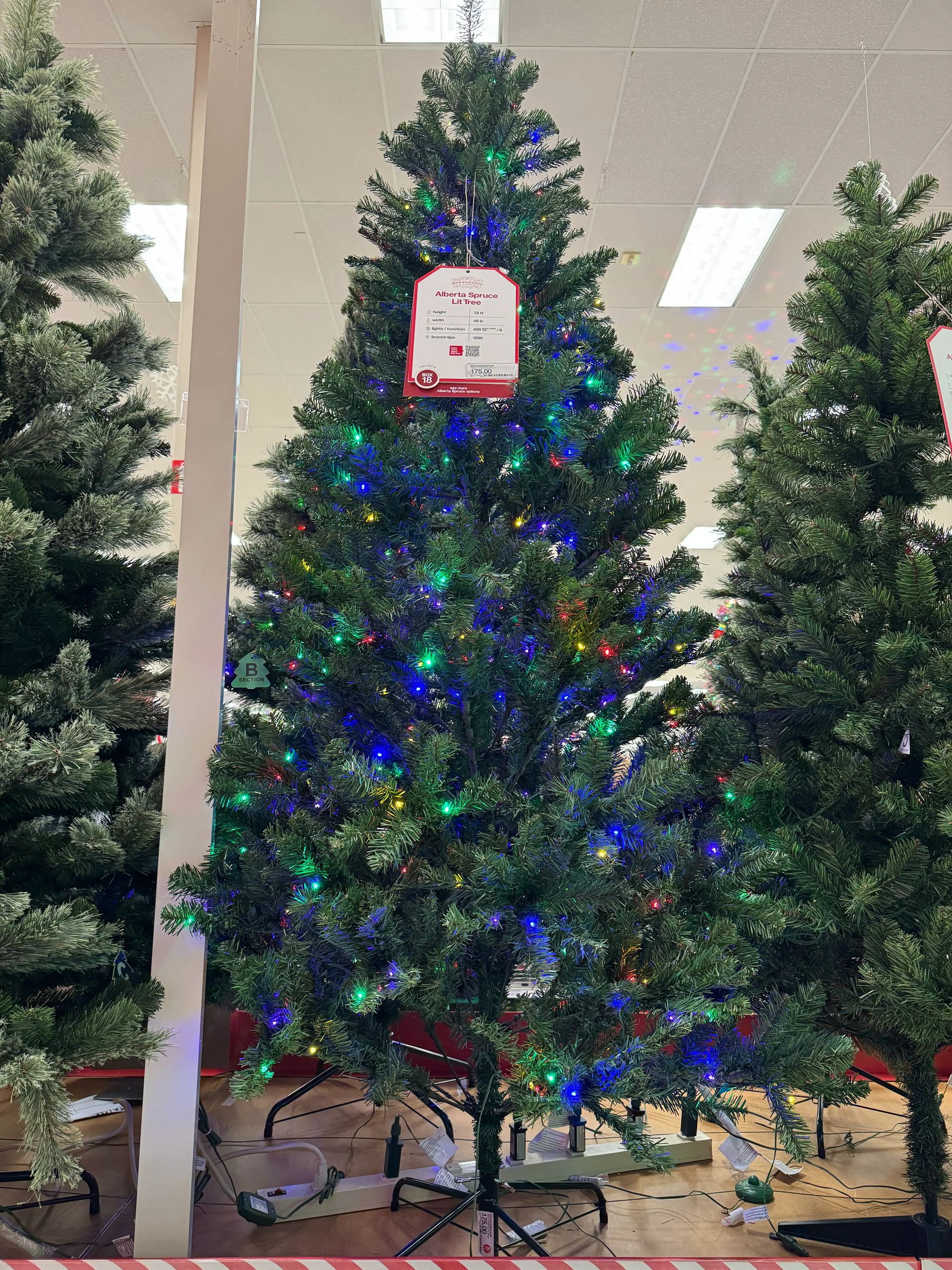 Traditional PVC spruce with moderate density, multicolor mini bulbs throughout, some visible gaps, full shape