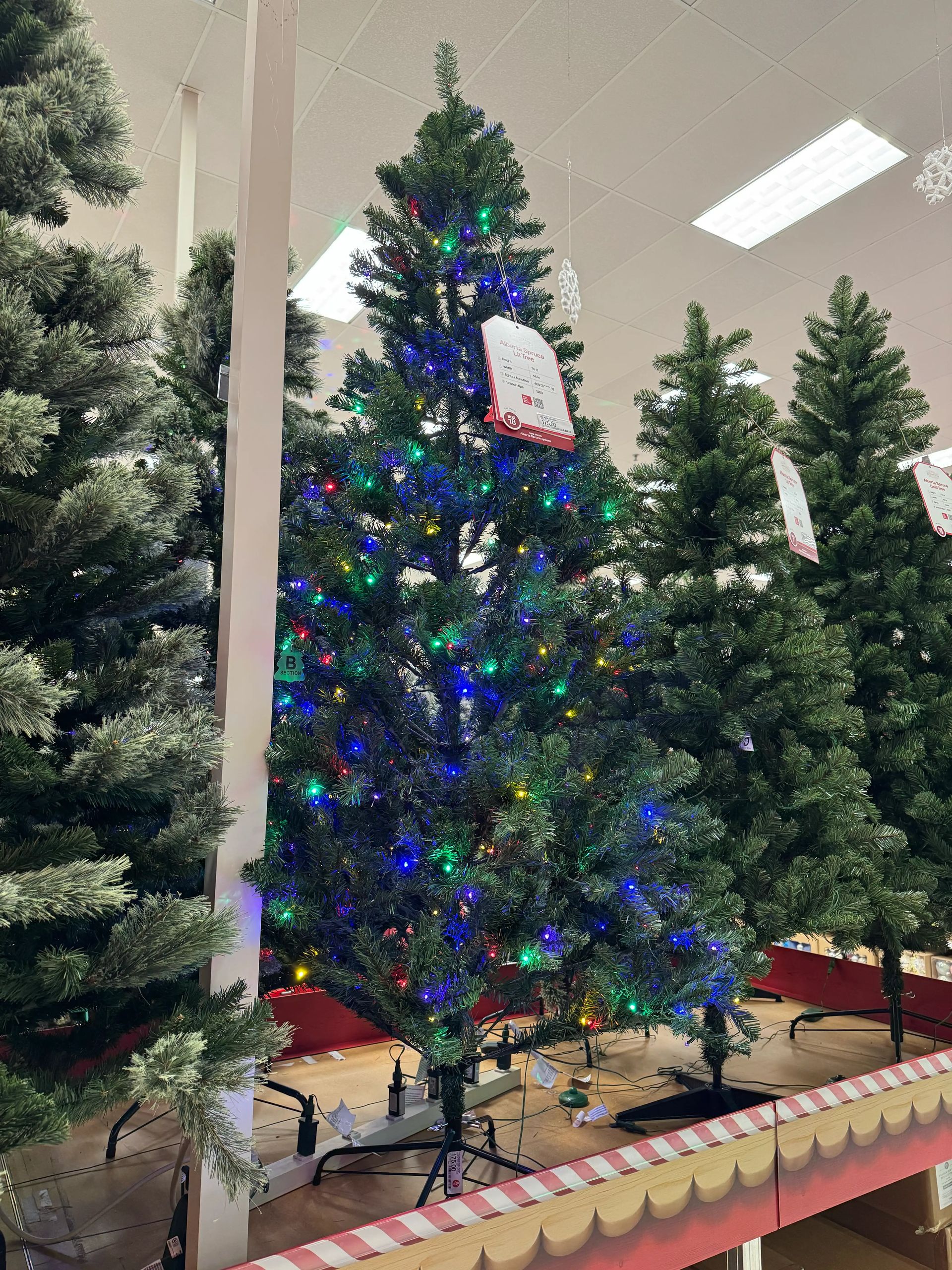 Traditional PVC spruce with moderate branching, visible gaps, multicolor mini bulbs densely distributed throughout