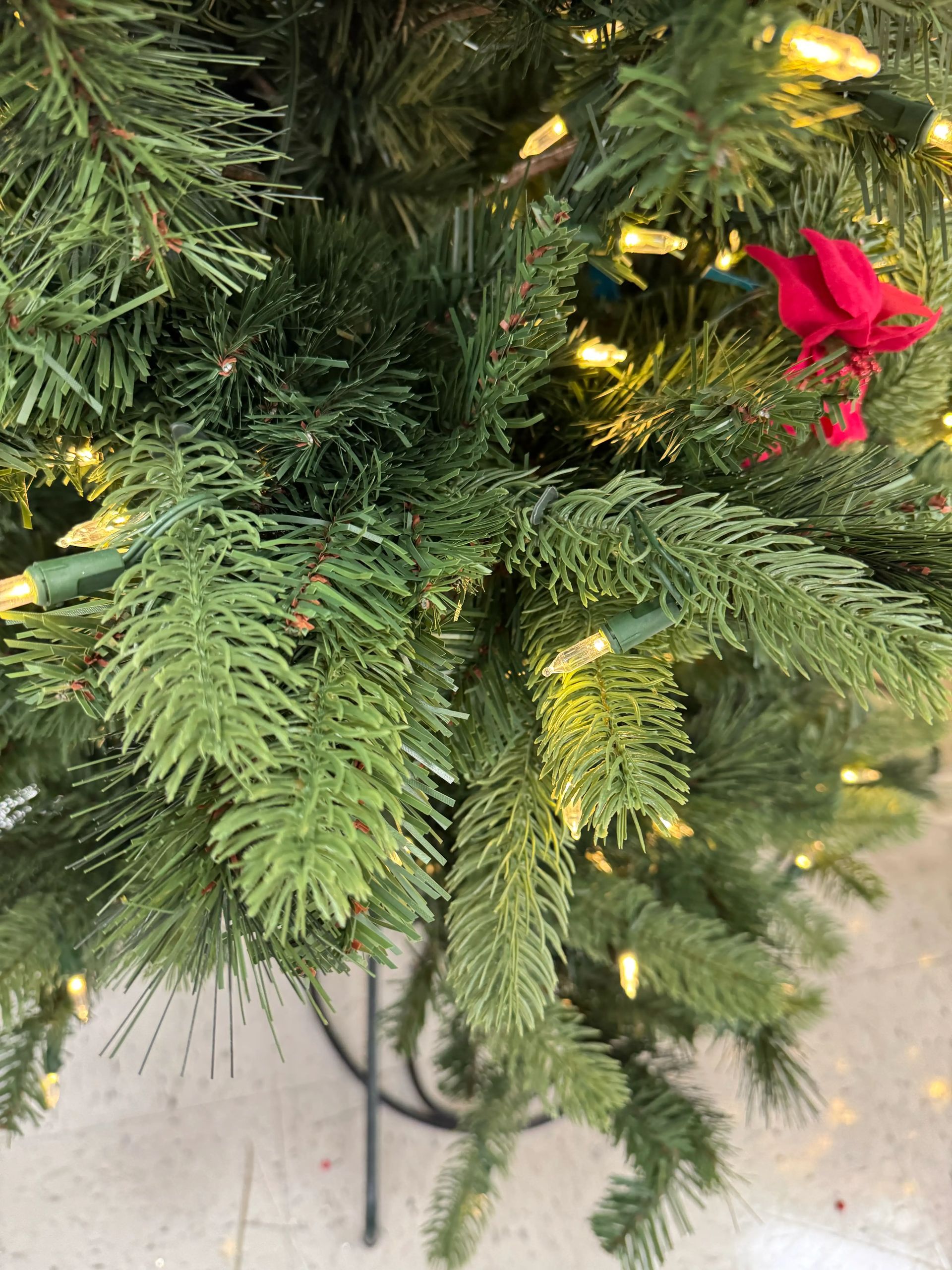 Mixed PVC and PE needle branches with warm white mini bulbs, moderate density, visible green wiring, red ornament accent