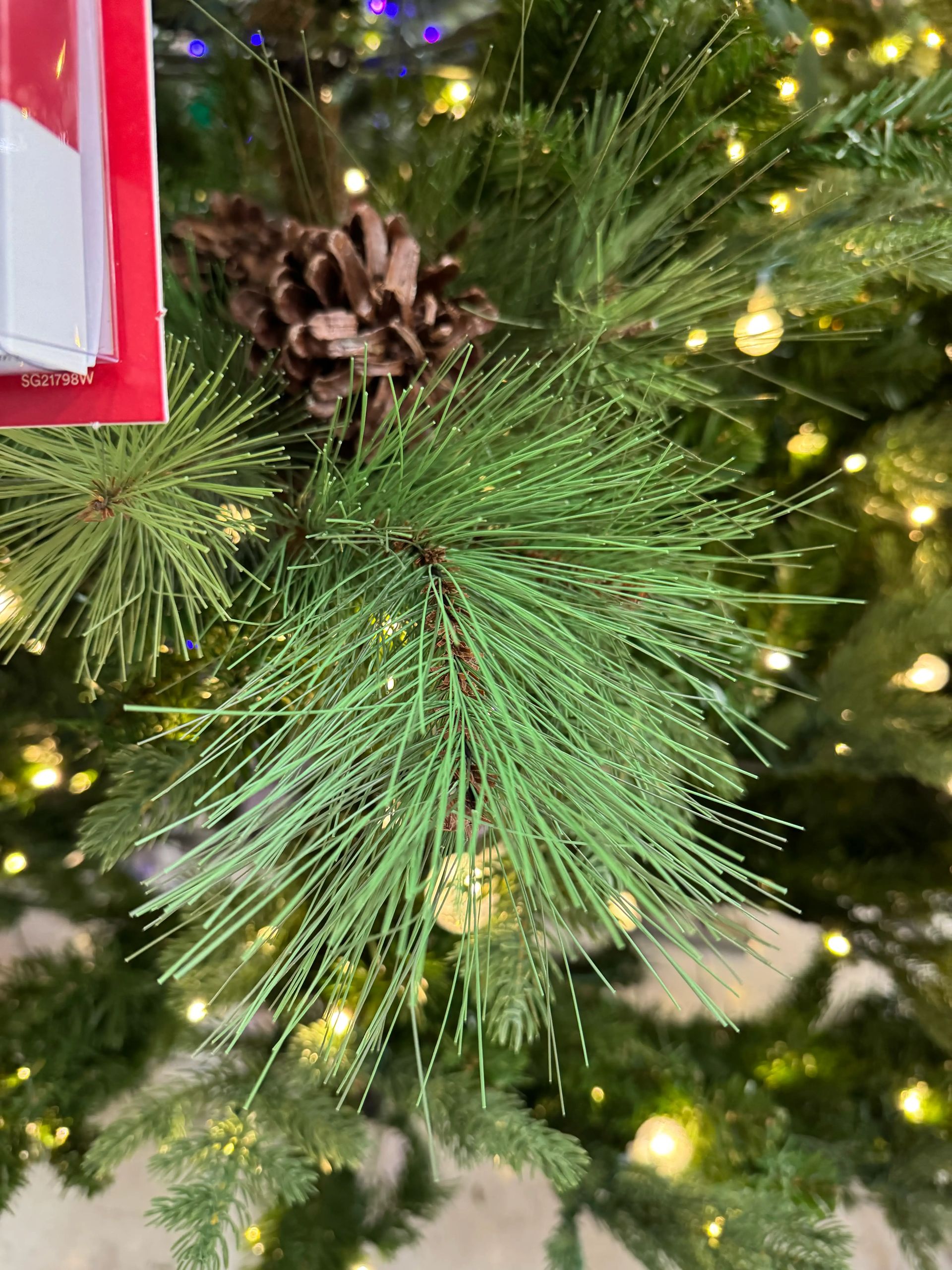 Long needle pine branch with brown pinecone, sparse warm white lights, mix of PVC and realistic PE needles visible