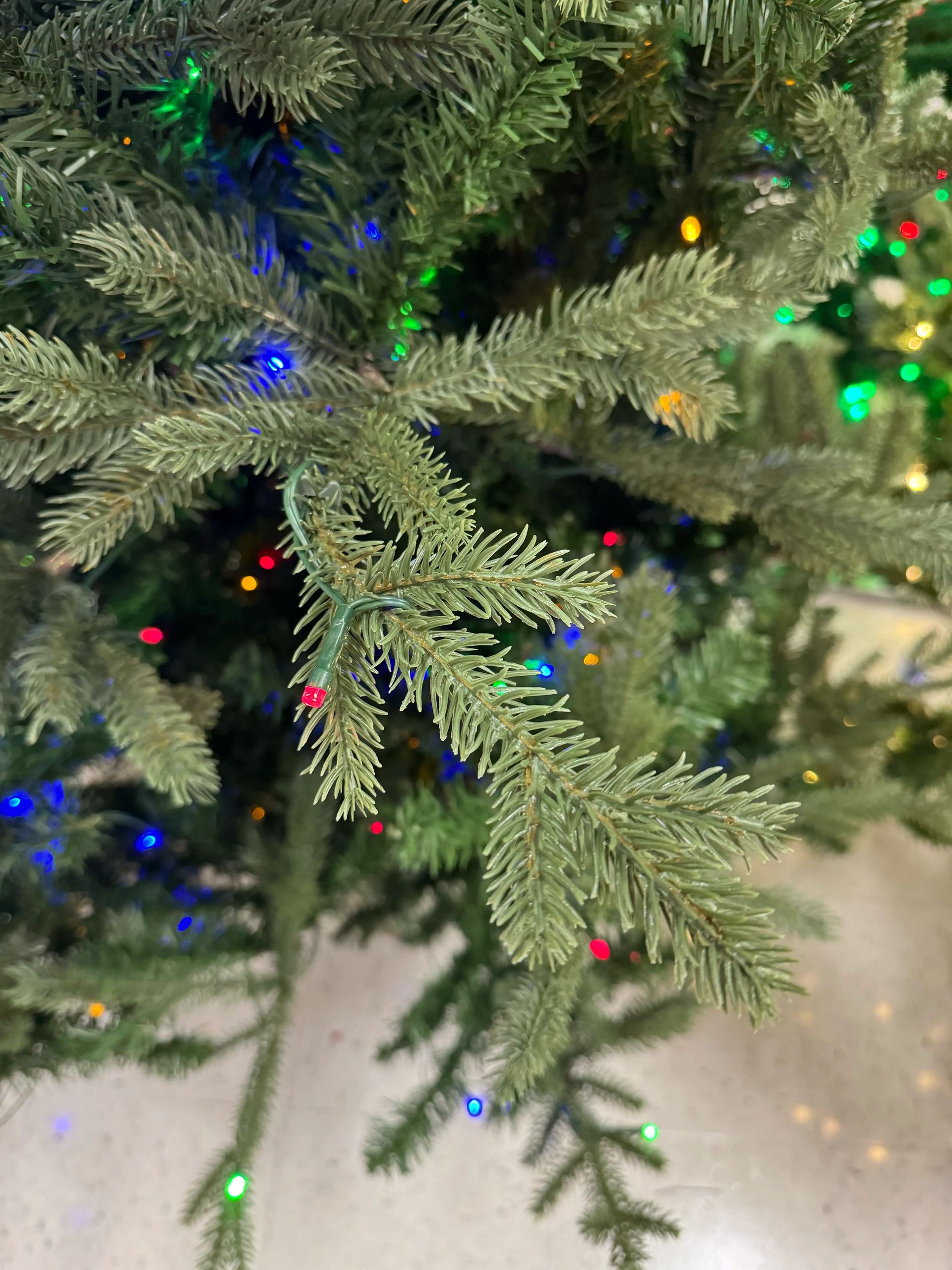 Mixed PVC/PE fir needles in sage green, multicolor mini LED lights, moderate density with some visible gaps