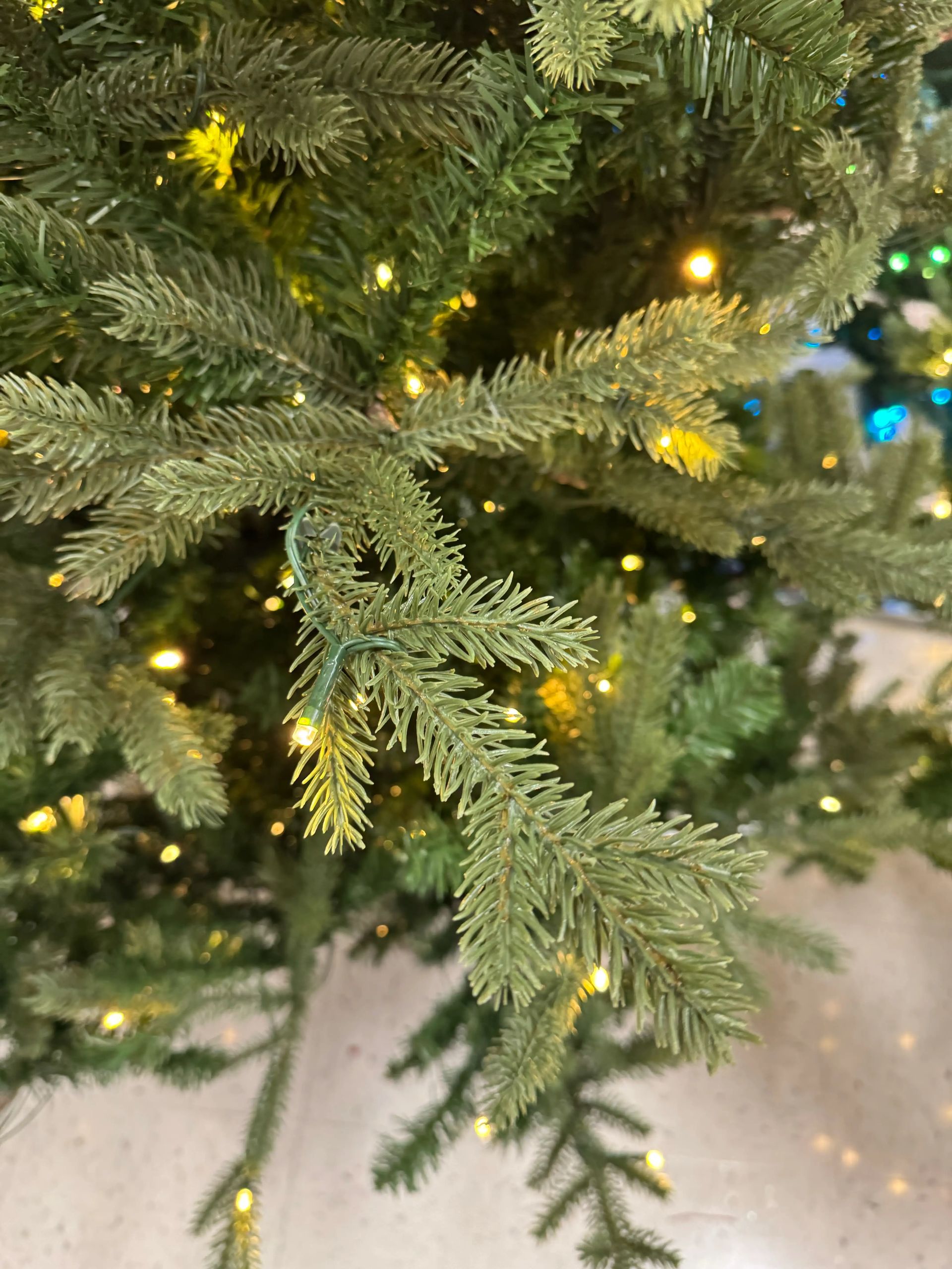 Mixed PVC and molded PE fir needles in green, warm white LED lights scattered throughout, moderate density branching