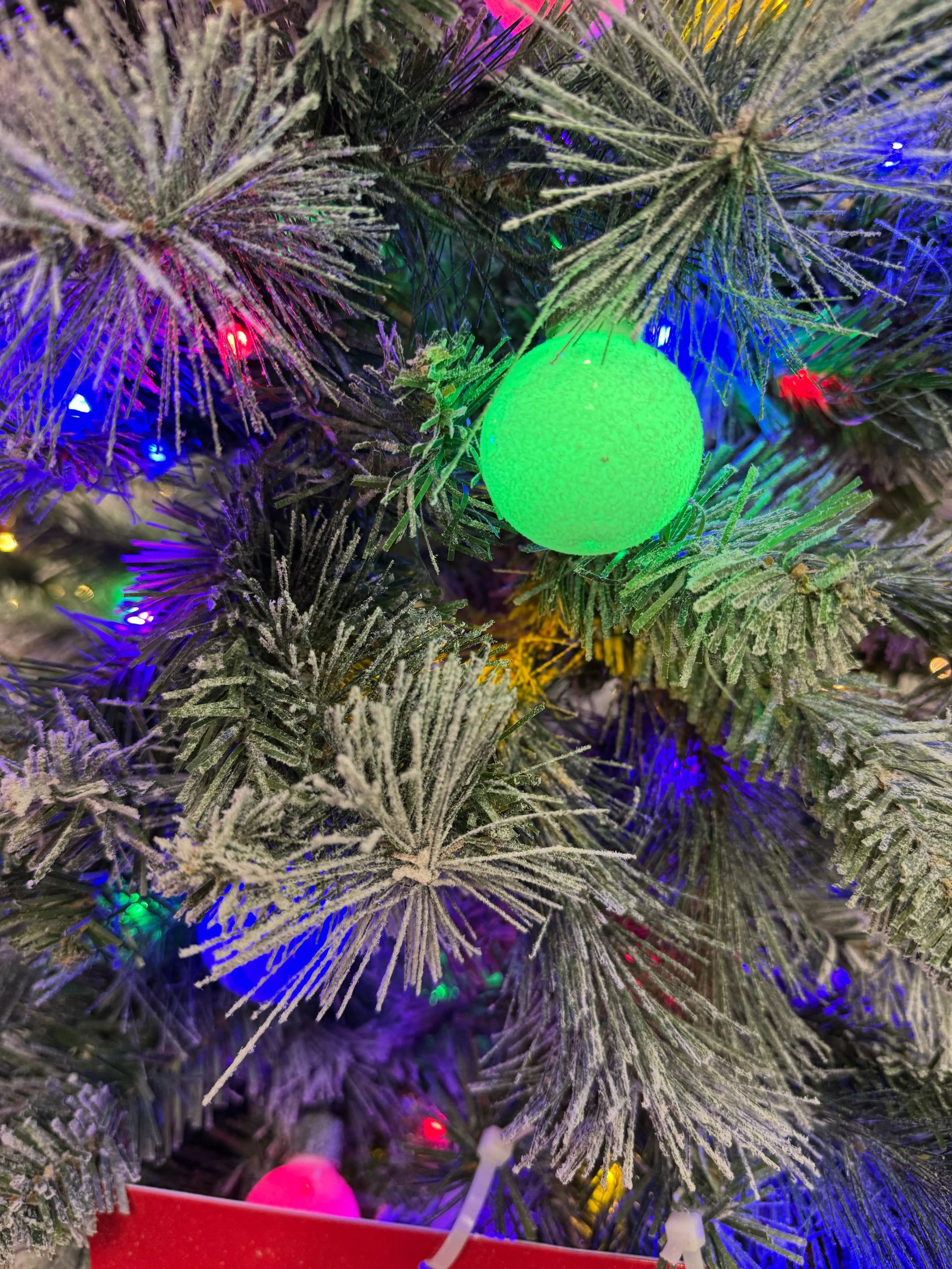 Flocked PVC pine needles with bright green LED globe bulb, multicolor mini lights scattered throughout branches