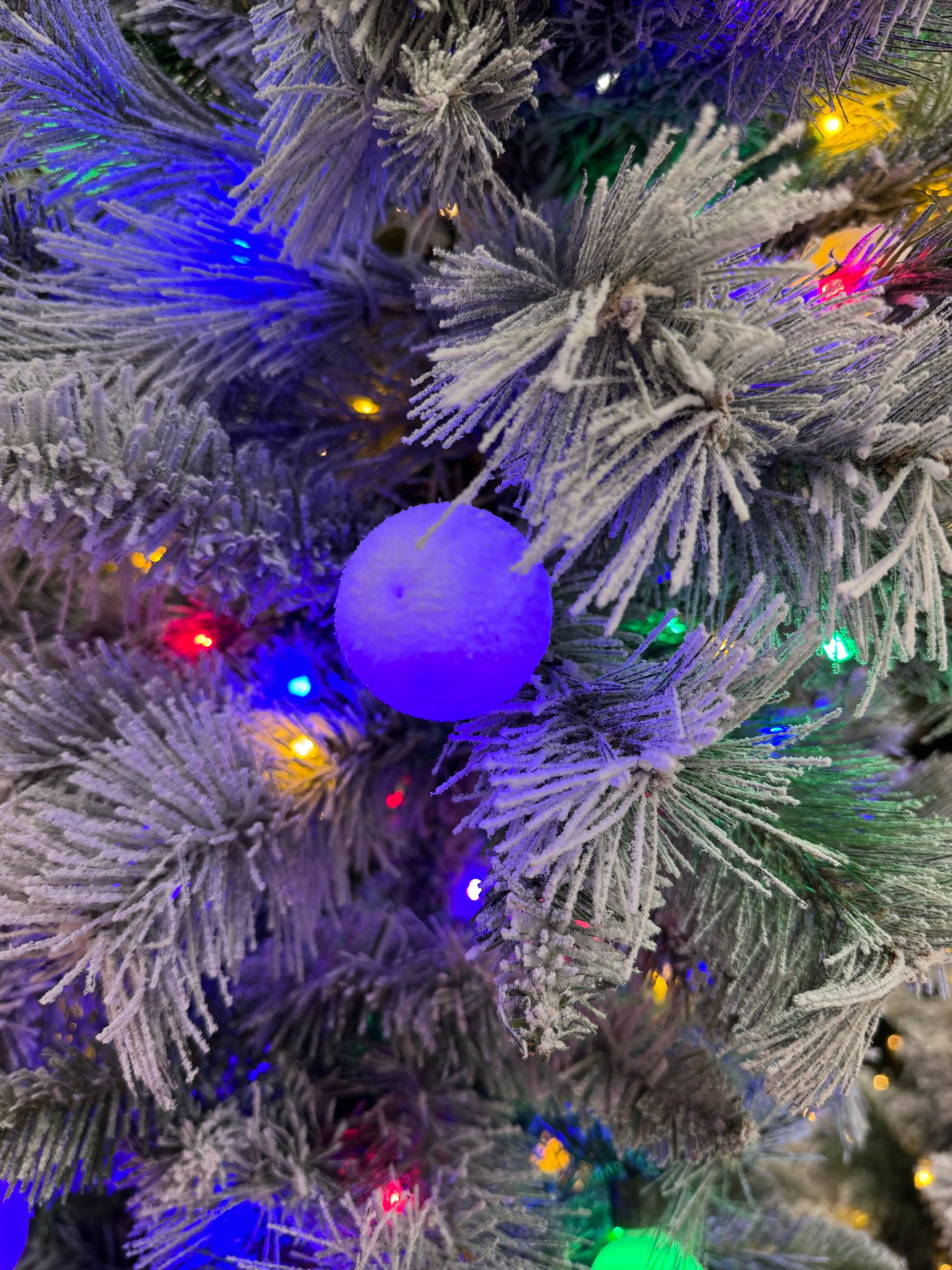 Frosted PVC fir needles with blue orb ornament, multicolor mini LED lights scattered throughout branches