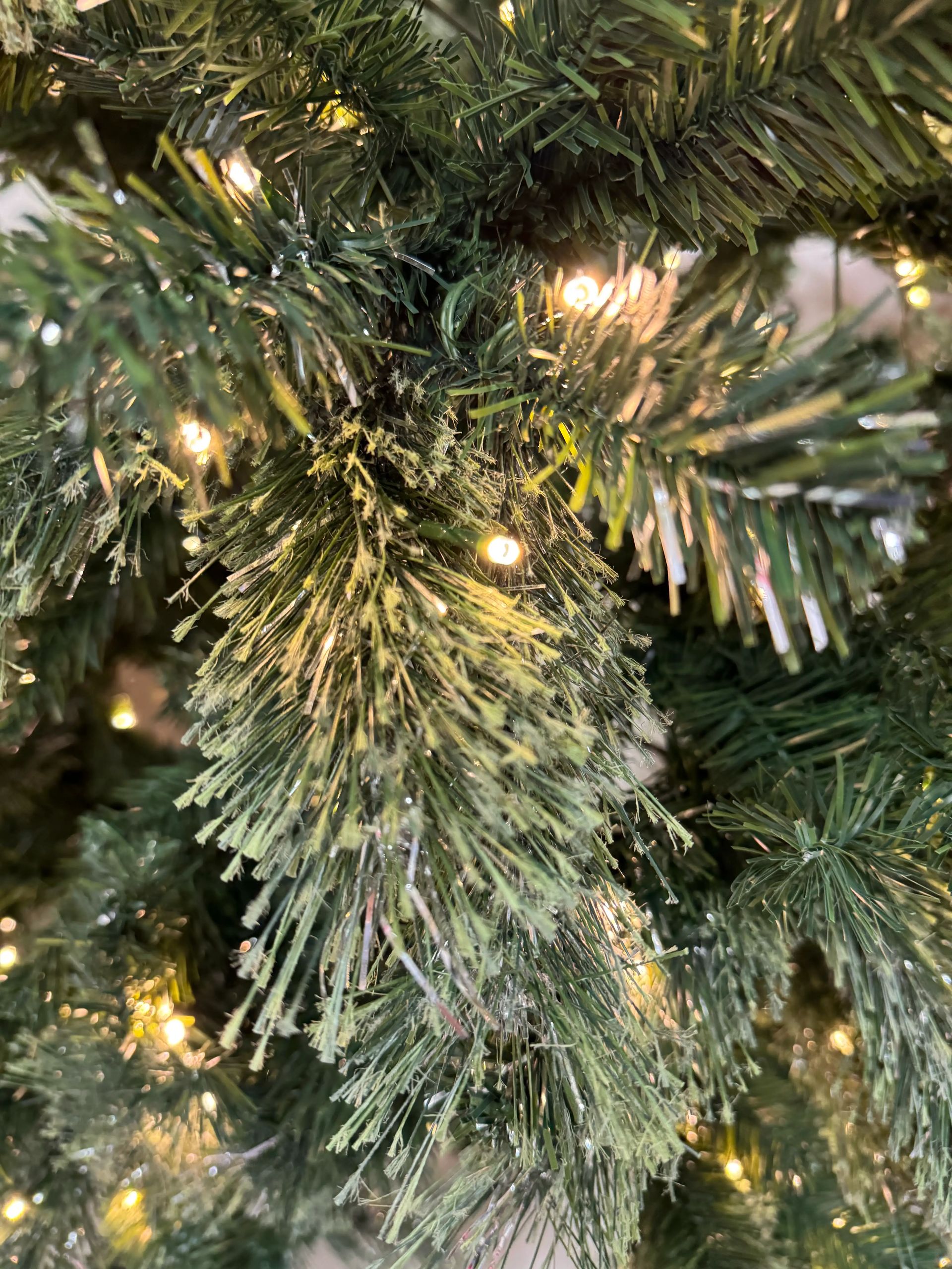 Dense PVC pine needles with silver tinsel strands throughout, warm white mini bulbs, textured frayed tips