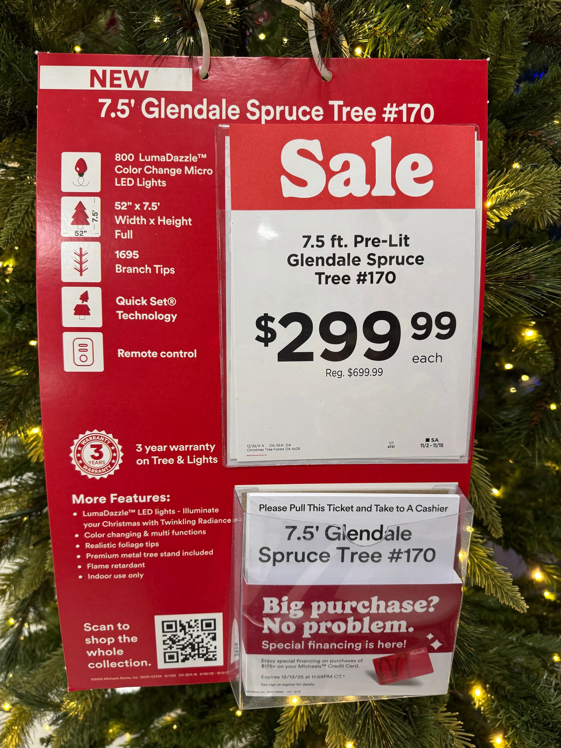 Sale sign showing 7.5ft pre-lit tree specs: 800 LumaDazzle LEDs, 1695 tips, remote control, $299.99 (reg $699.99)