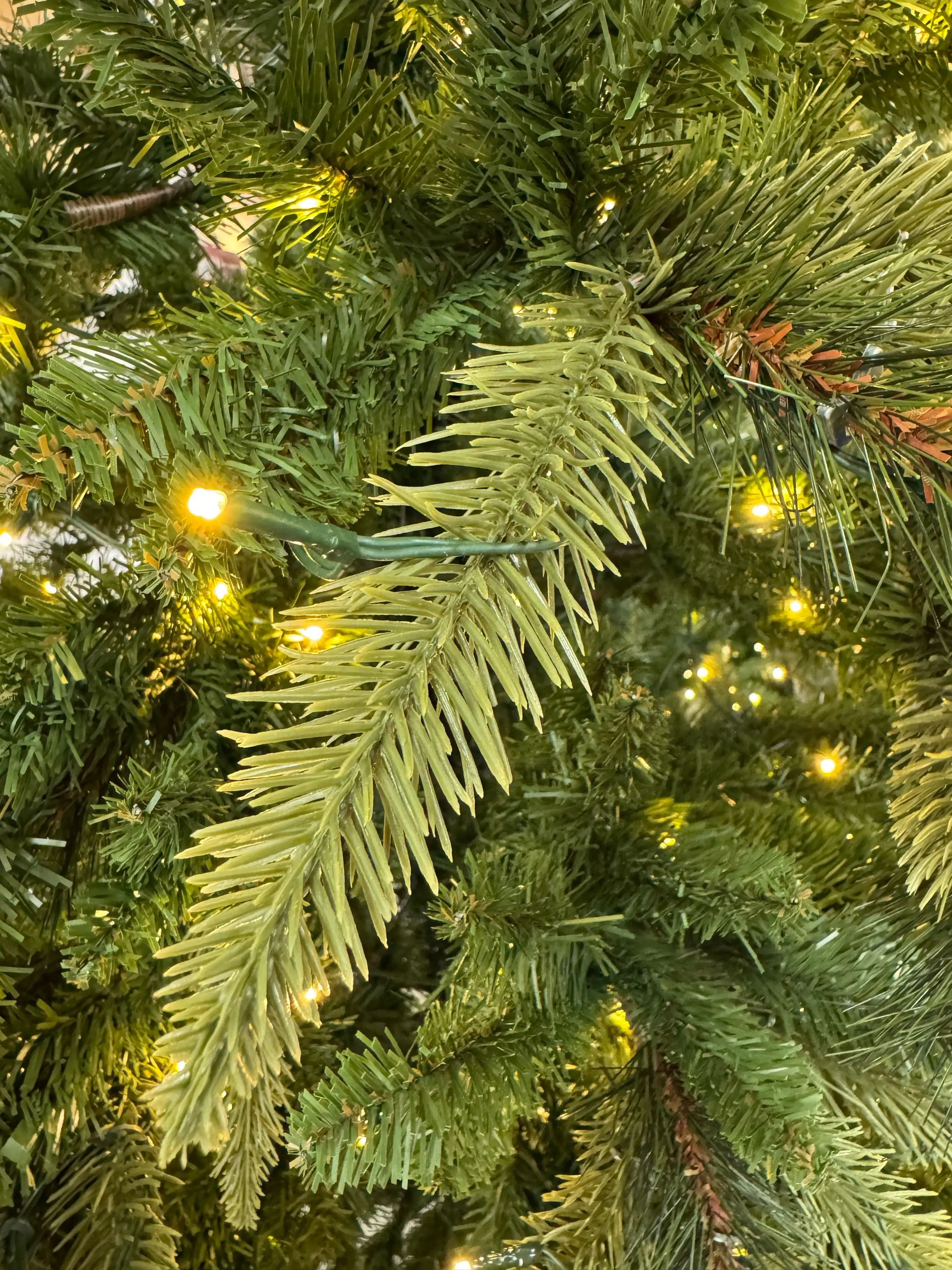 Mixed PVC and molded PE spruce needles in varying green tones, warm white LED lights scattered throughout branches
