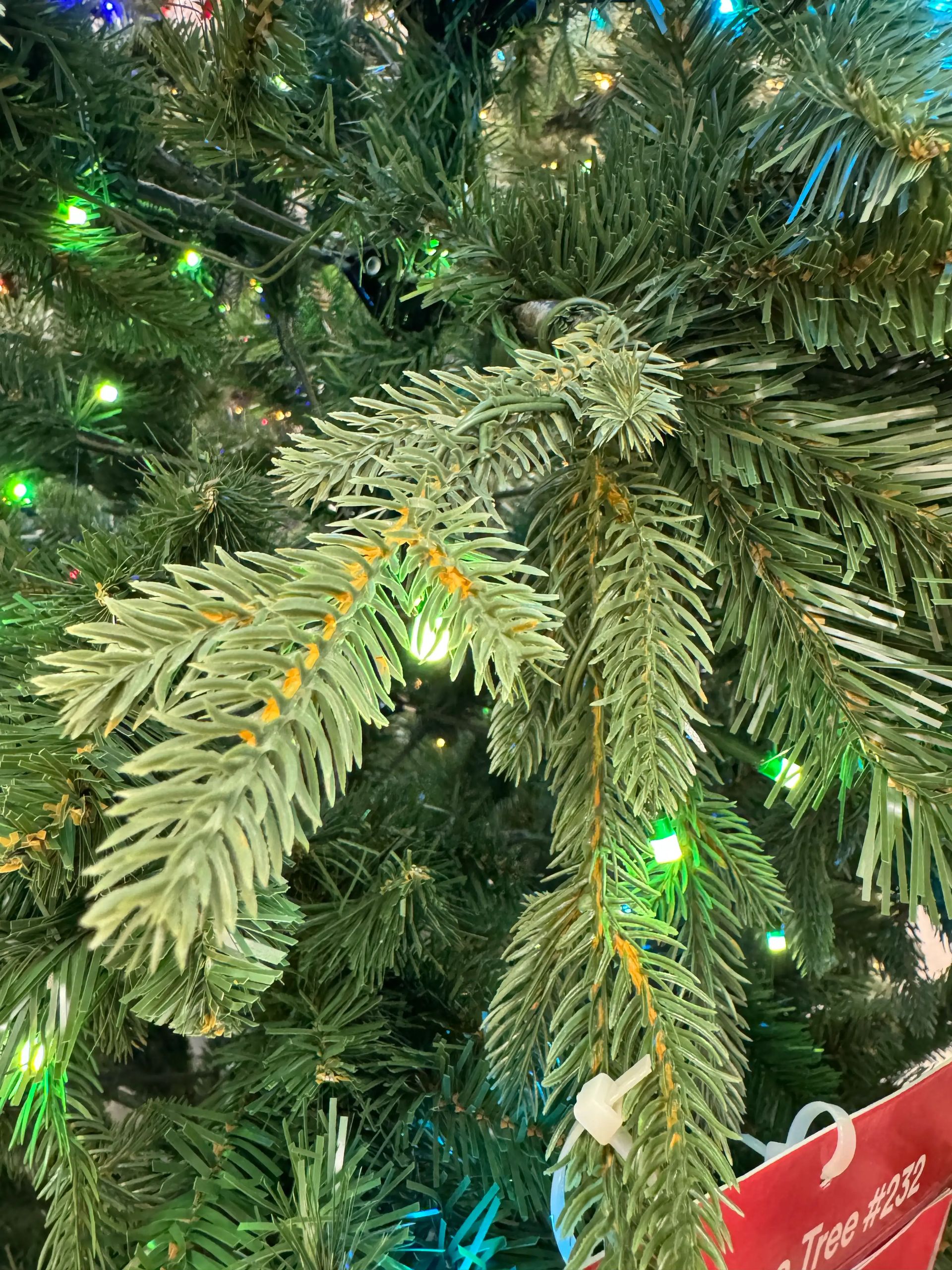 Close-up of spruce-style branches showing mixed PVC and PE needles with sparse green LED coverage and visible brown branch stems throughout.