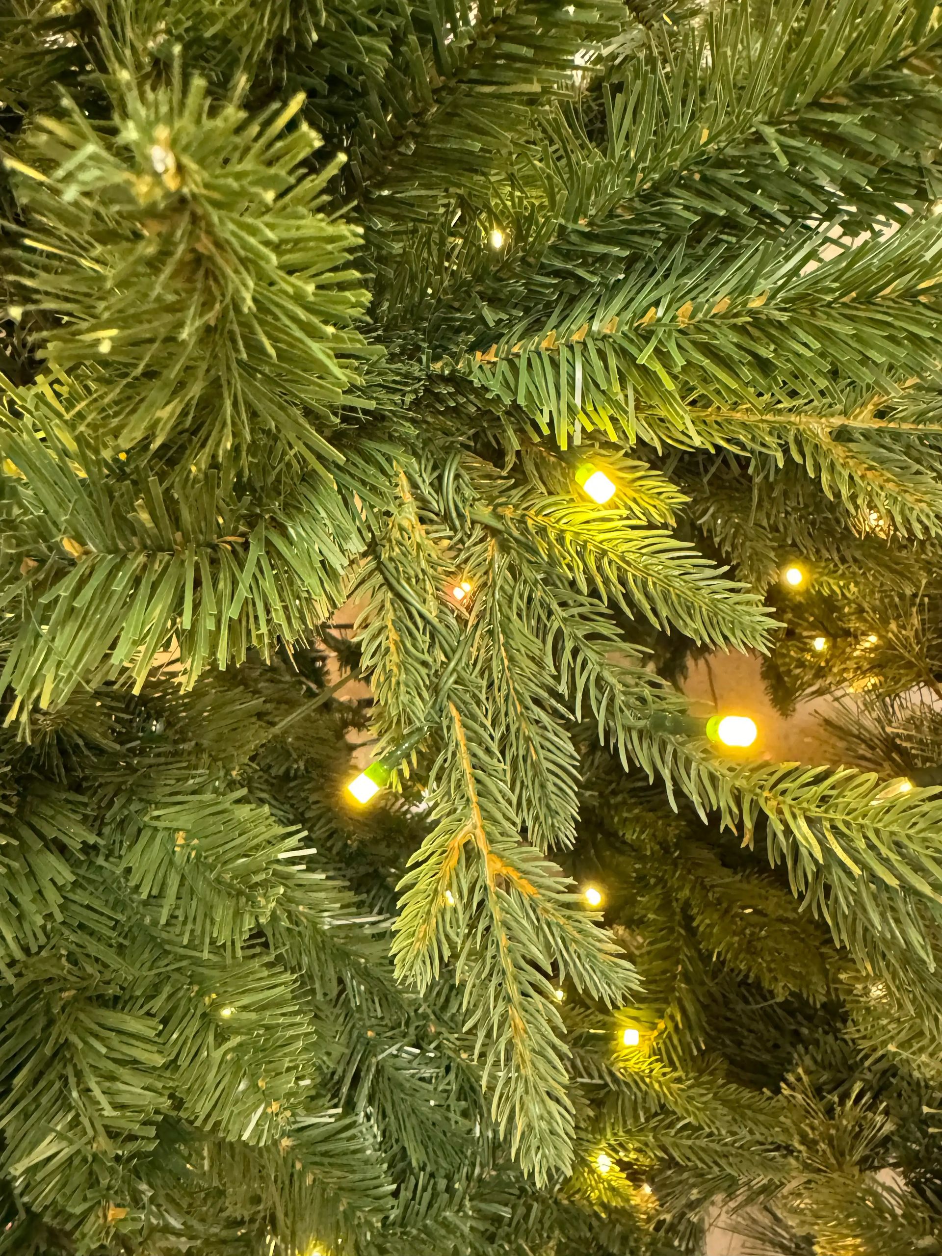 Mixed PVC and PE spruce needles in varying green tones, warm white mini bulbs dispersed throughout branches