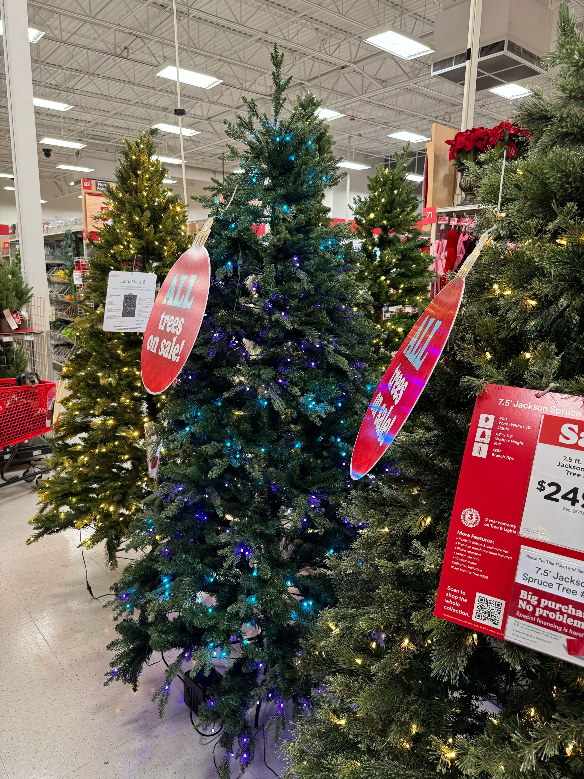 Full spruce-style tree with dense PVC branches, multicolor lights (blue, purple, warm white), minimal gaps, wide shape