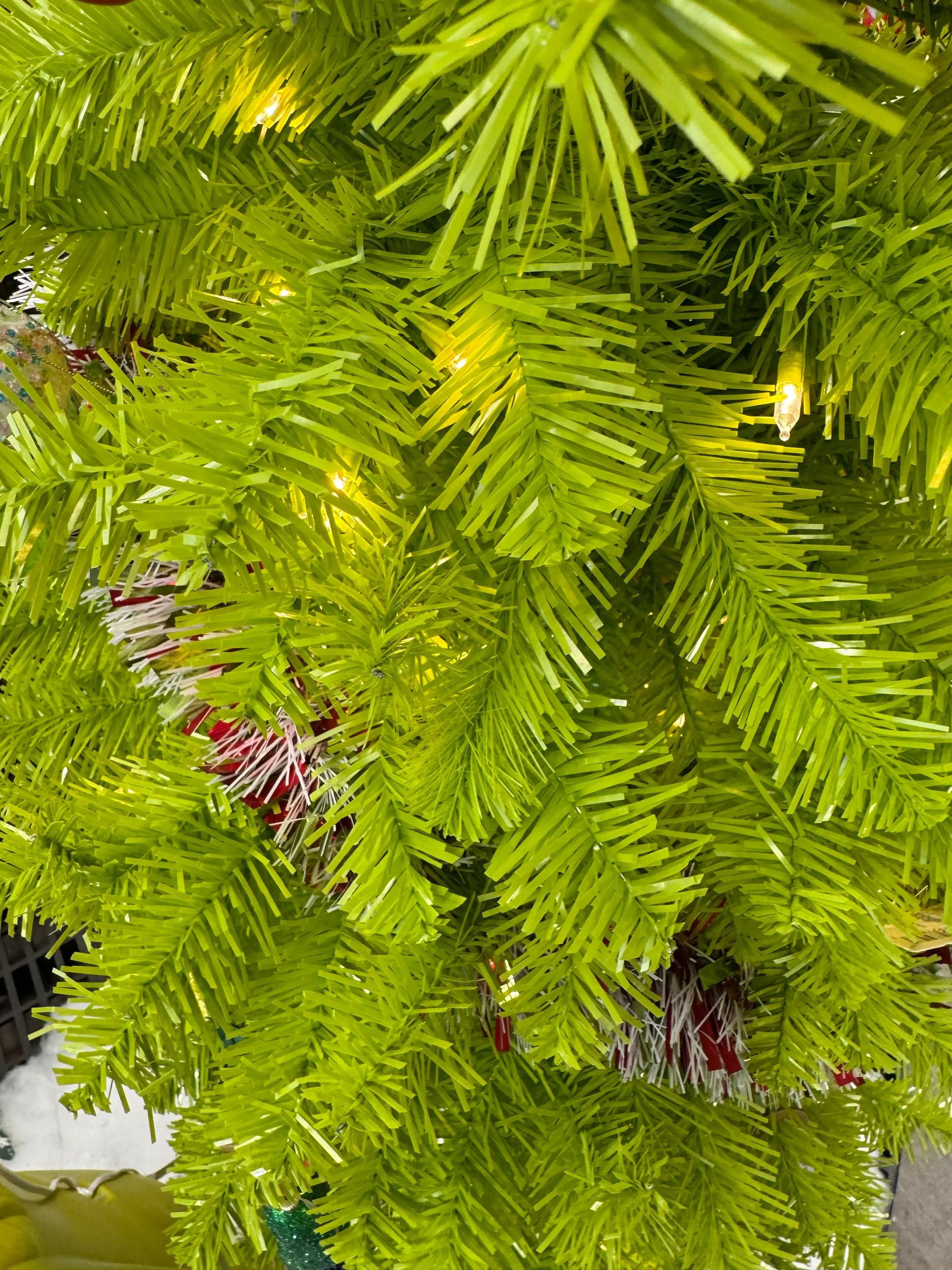 Bright lime-green PVC spruce needles, warm white mini LED bulbs visible, moderate branch density with some gaps