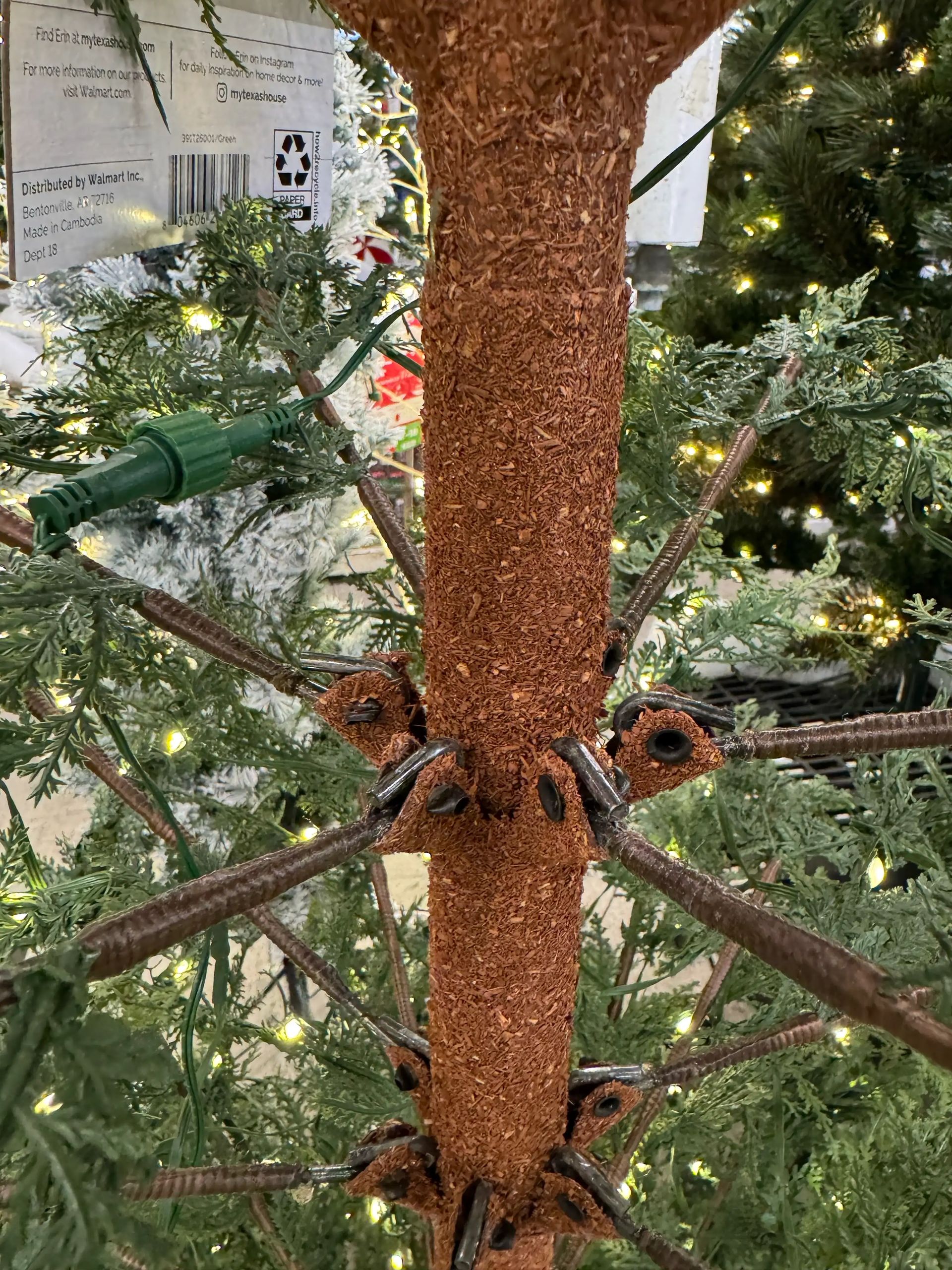 Brown textured trunk with wire branches extending radially, secured with looped attachments, visible mechanical construction