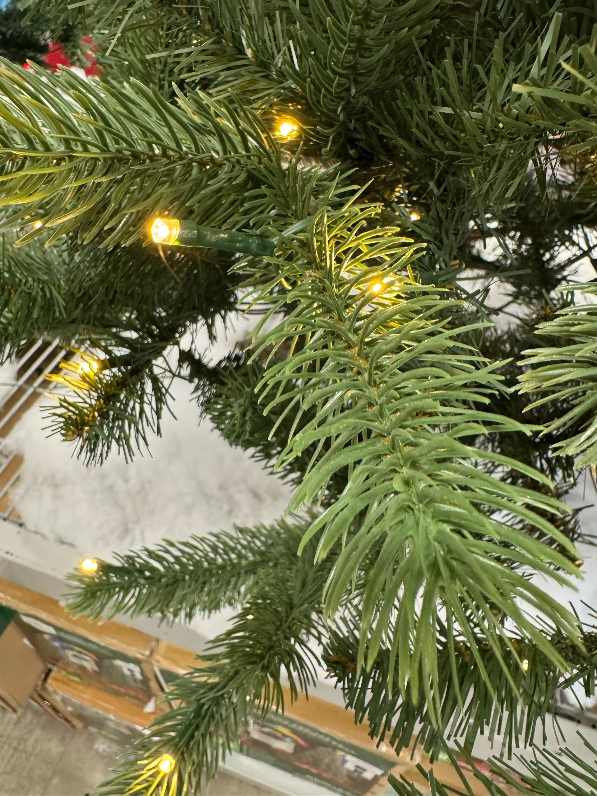 Mixed PVC and molded PE fir needles, warm white mini LED lights wired along branches, moderate density with some gaps