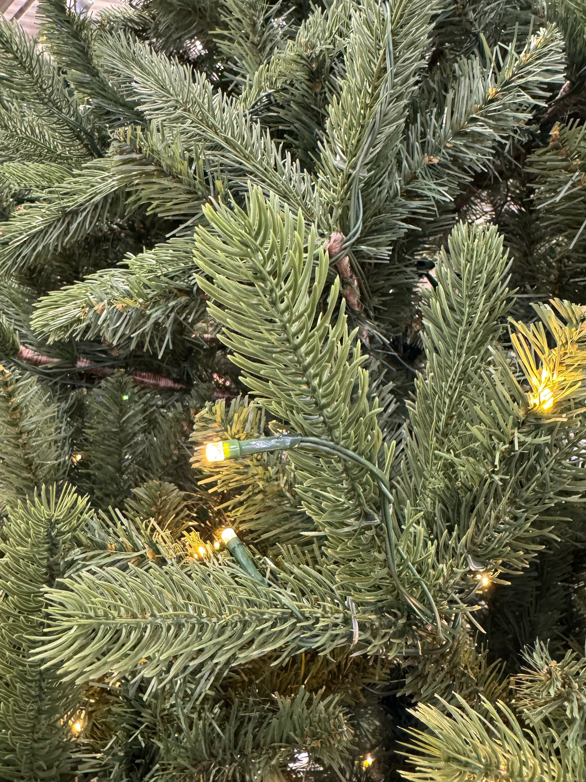 Mixed PVC and molded PE needles in sage-green tones, warm white micro LEDs visible, moderate branch density