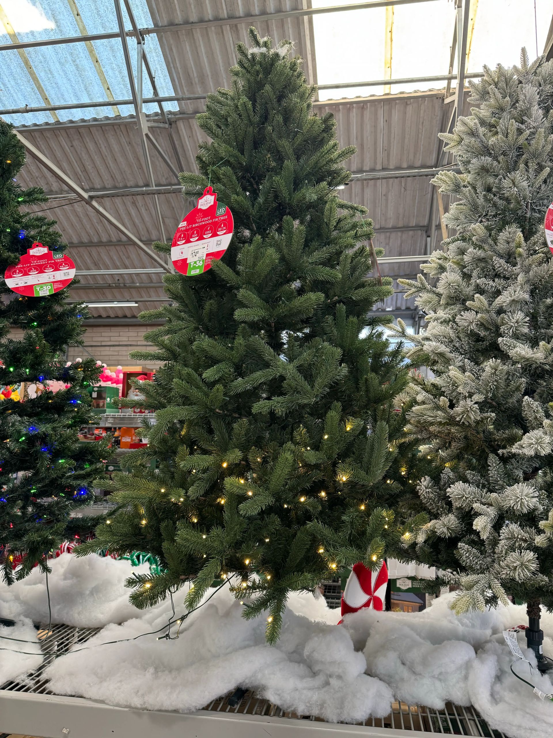 Full fir-style tree with moderate PVC branching, visible gaps between layers, warm white LED lights evenly distributed