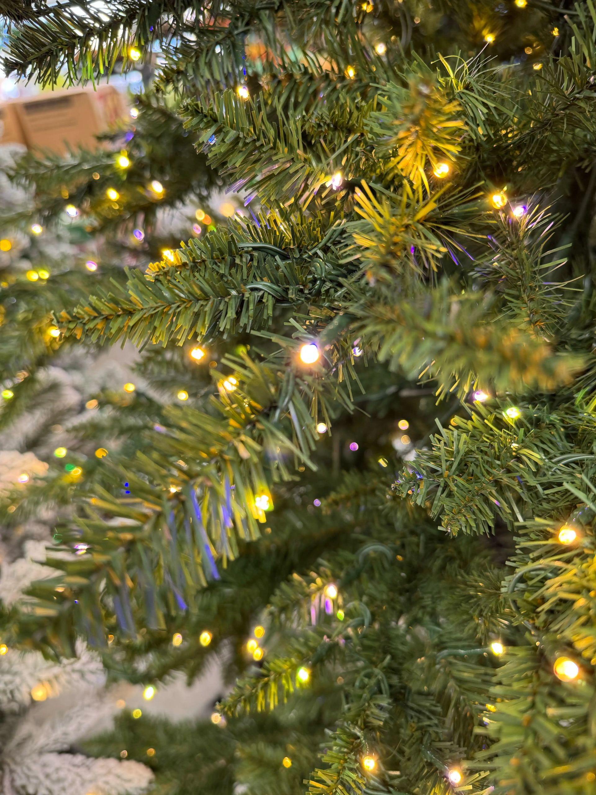 Dense PVC pine needles with warm white and multicolor LED lights distributed throughout branches, minimal gaps visible