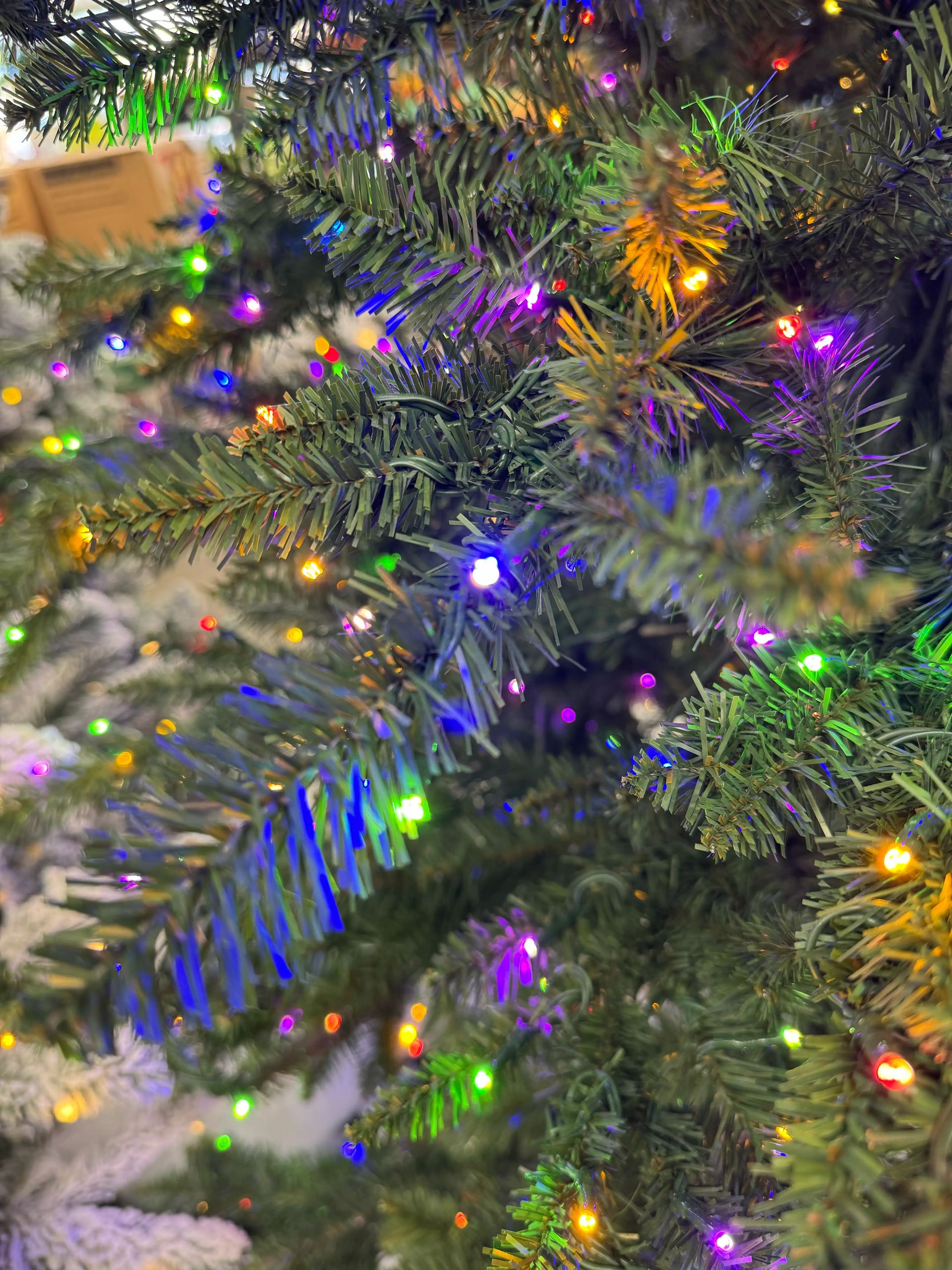 Dense PVC pine needles with multicolor LED lights, purple and orange hues visible, moderate light coverage throughout
