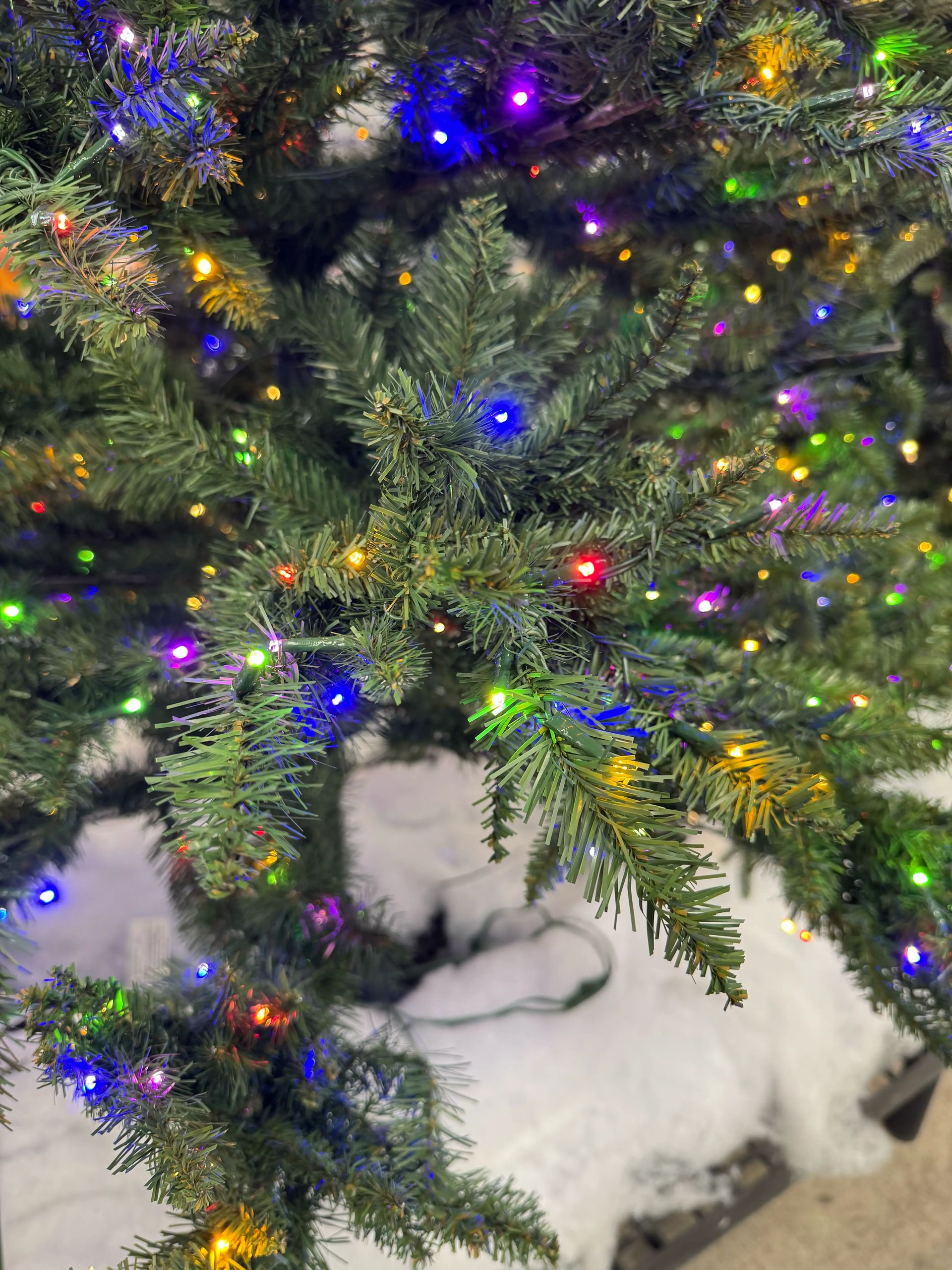 Moderate PVC pine needles with multicolor LED lights, visible brown stems, white fuzzy decoration at base