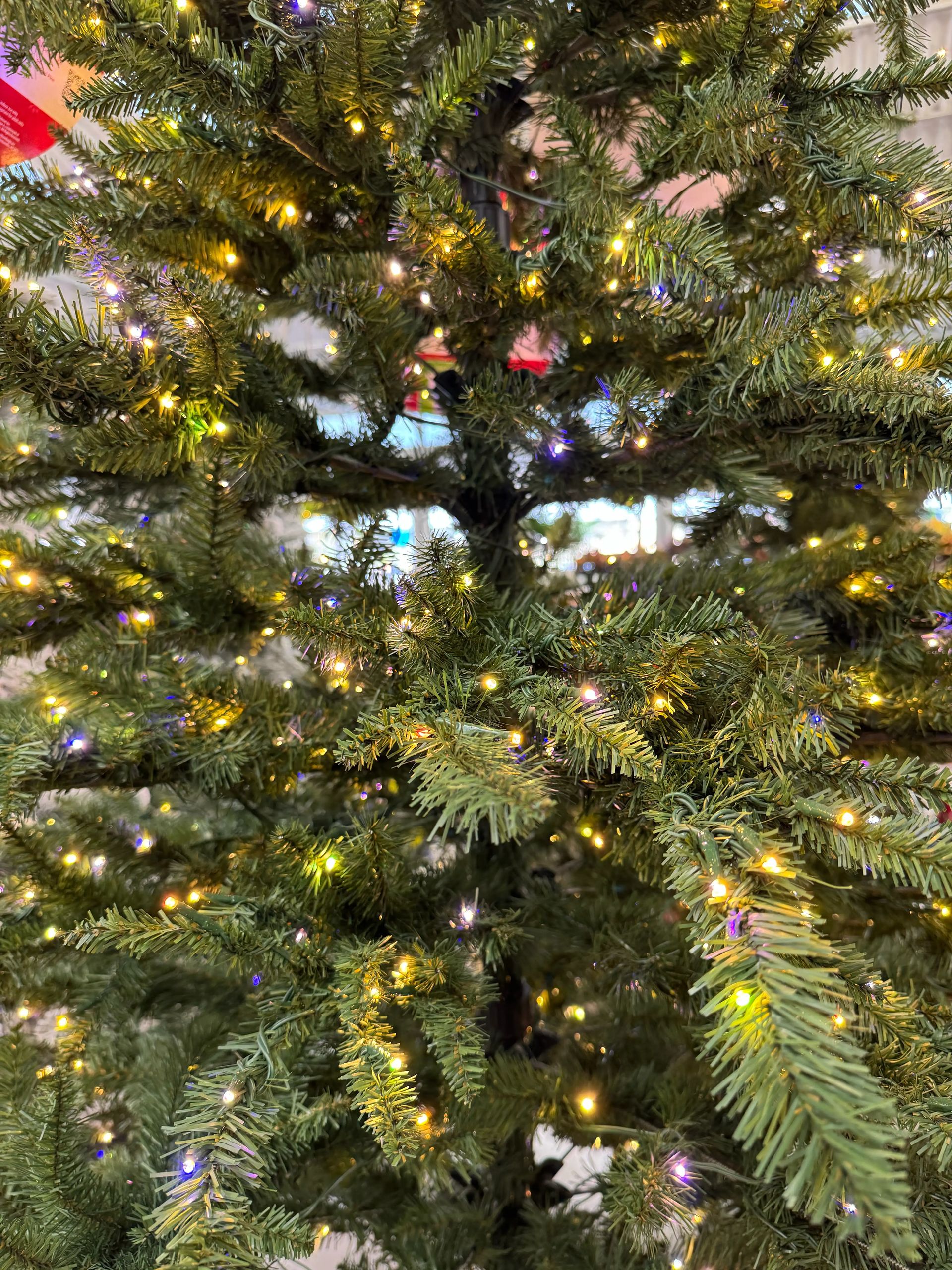 Dense PVC pine branches with warm white and blue LED lights throughout, minimal visible gaps, dark green needles