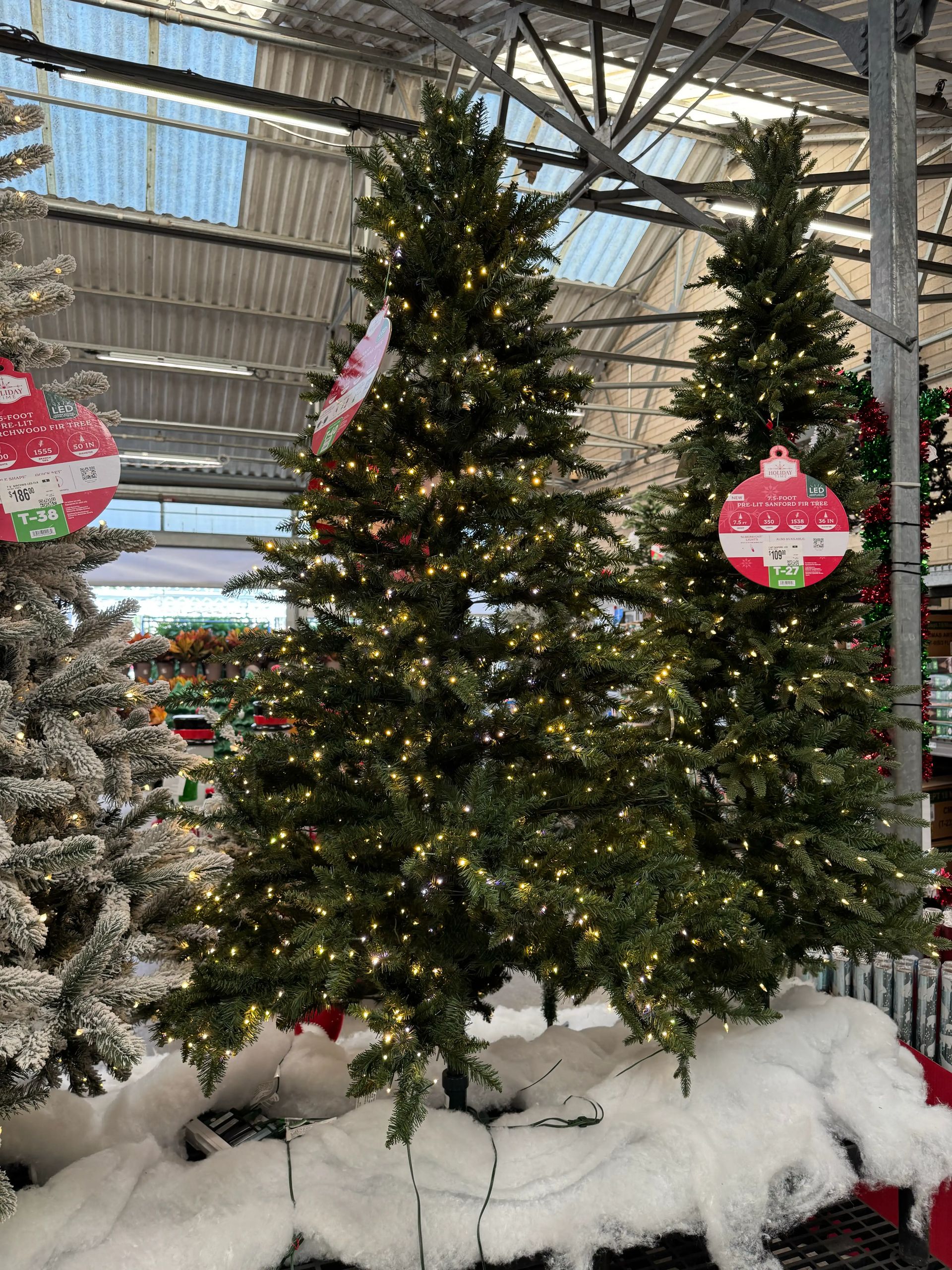 Full pine-style tree with moderate PVC branching, visible gaps in structure, warm white mini bulbs throughout