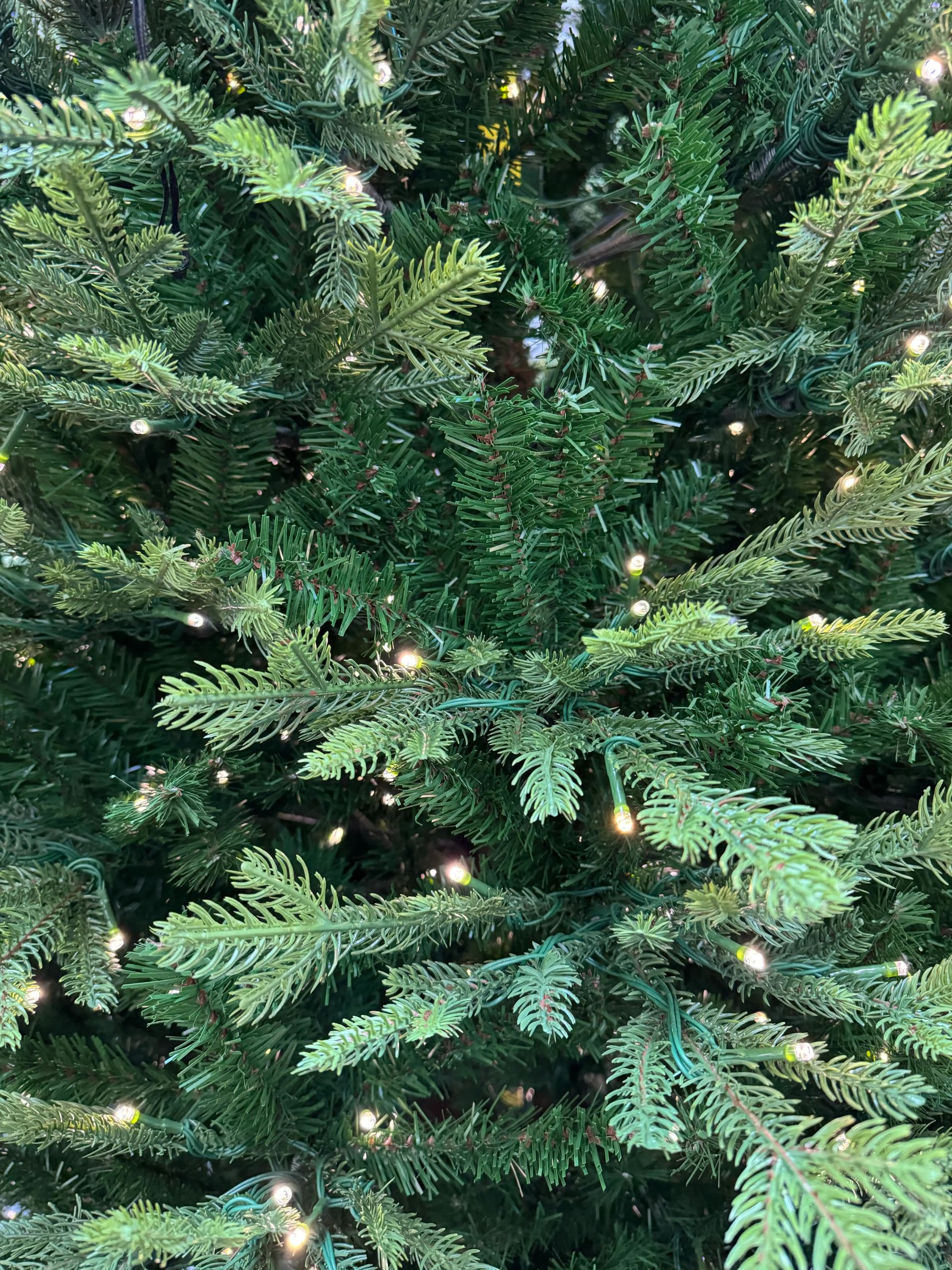 Mixed PVC and PE fir needles in varying green shades, warm white micro LEDs distributed throughout, moderate density