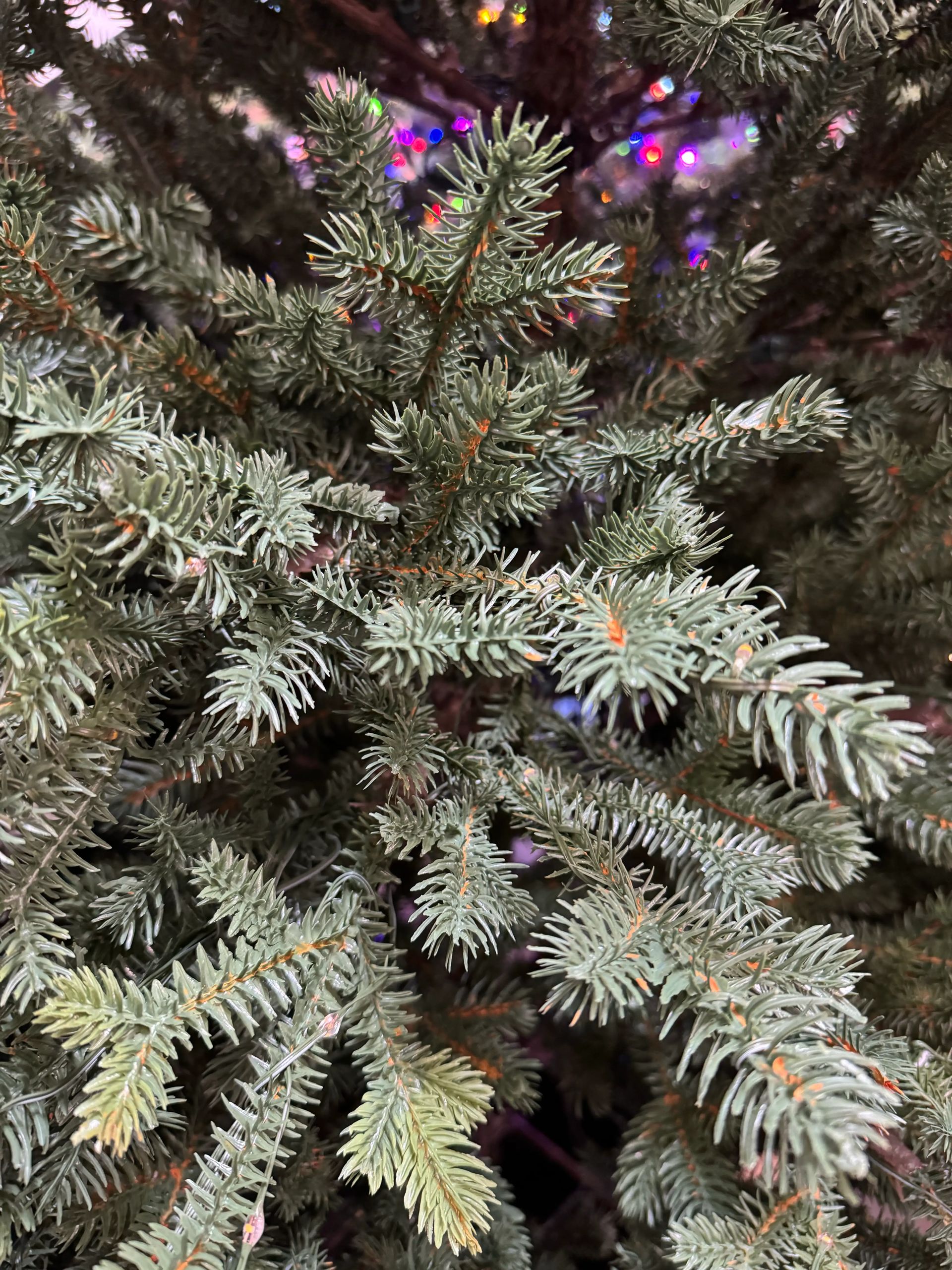Dense molded PE fir needles with frosted tips, warm micro LEDs visible in background, realistic texture