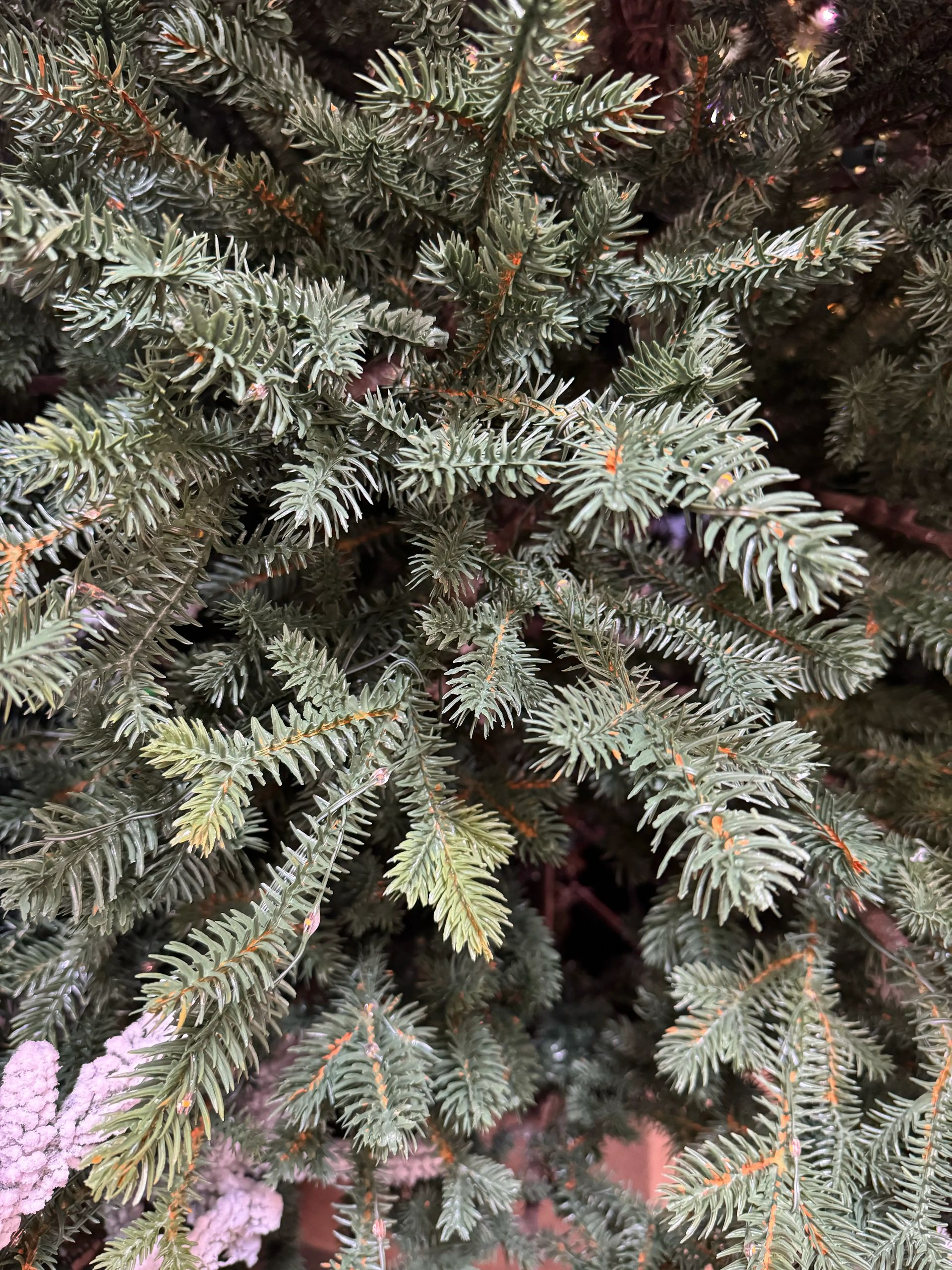 Dense molded PE fir needles in sage green with realistic texture, tight branch coverage, purple lights visible at edges