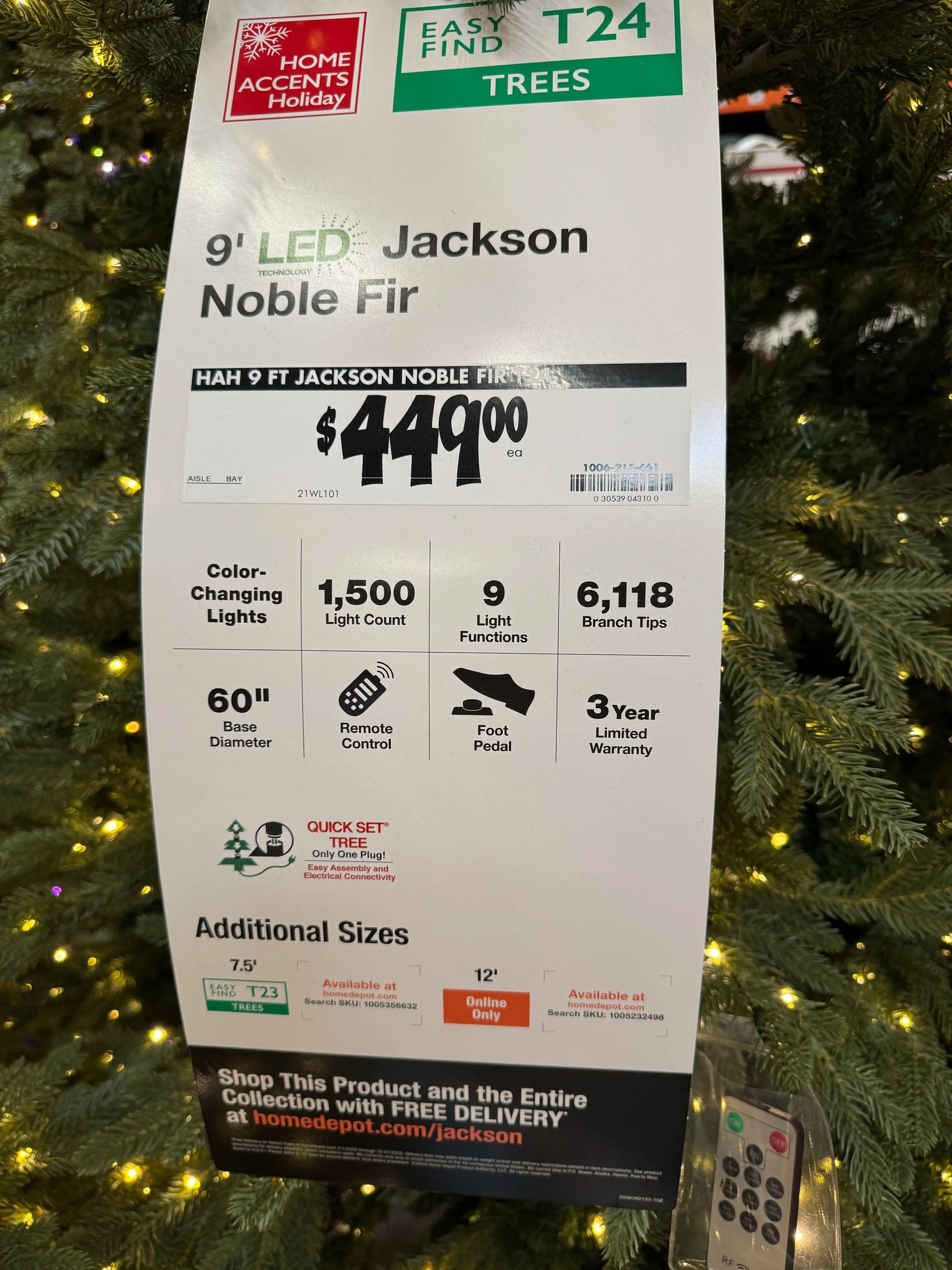 Product sign for 9ft Jackson Noble Fir: $449, 1,500 color-changing LEDs, 9 functions, remote, 60in base, 3yr warranty