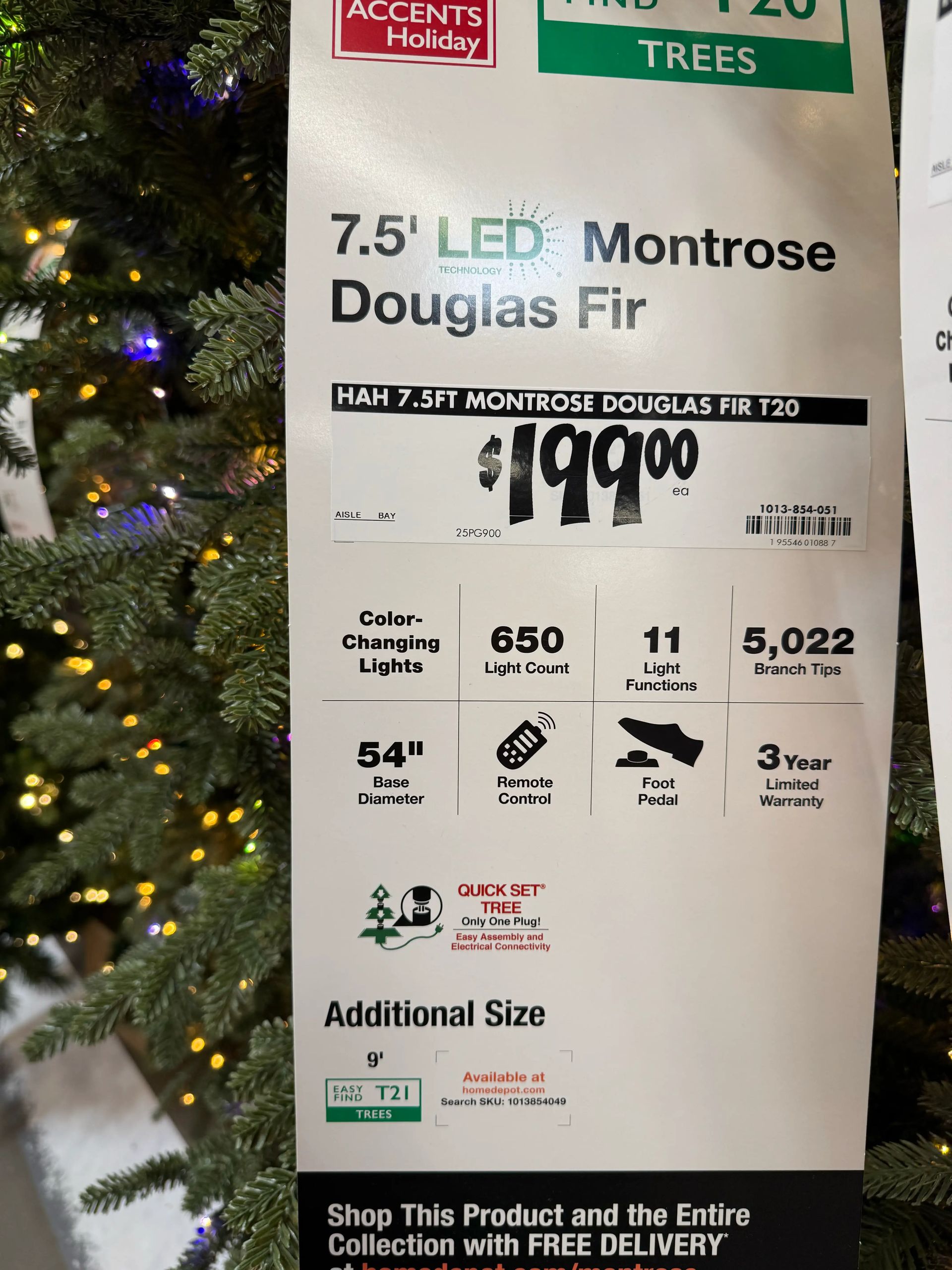 Product sign showing 7.5ft tree specs: $199, 650 lights, 11 functions, 5,022 tips, 54in base, remote & foot pedal