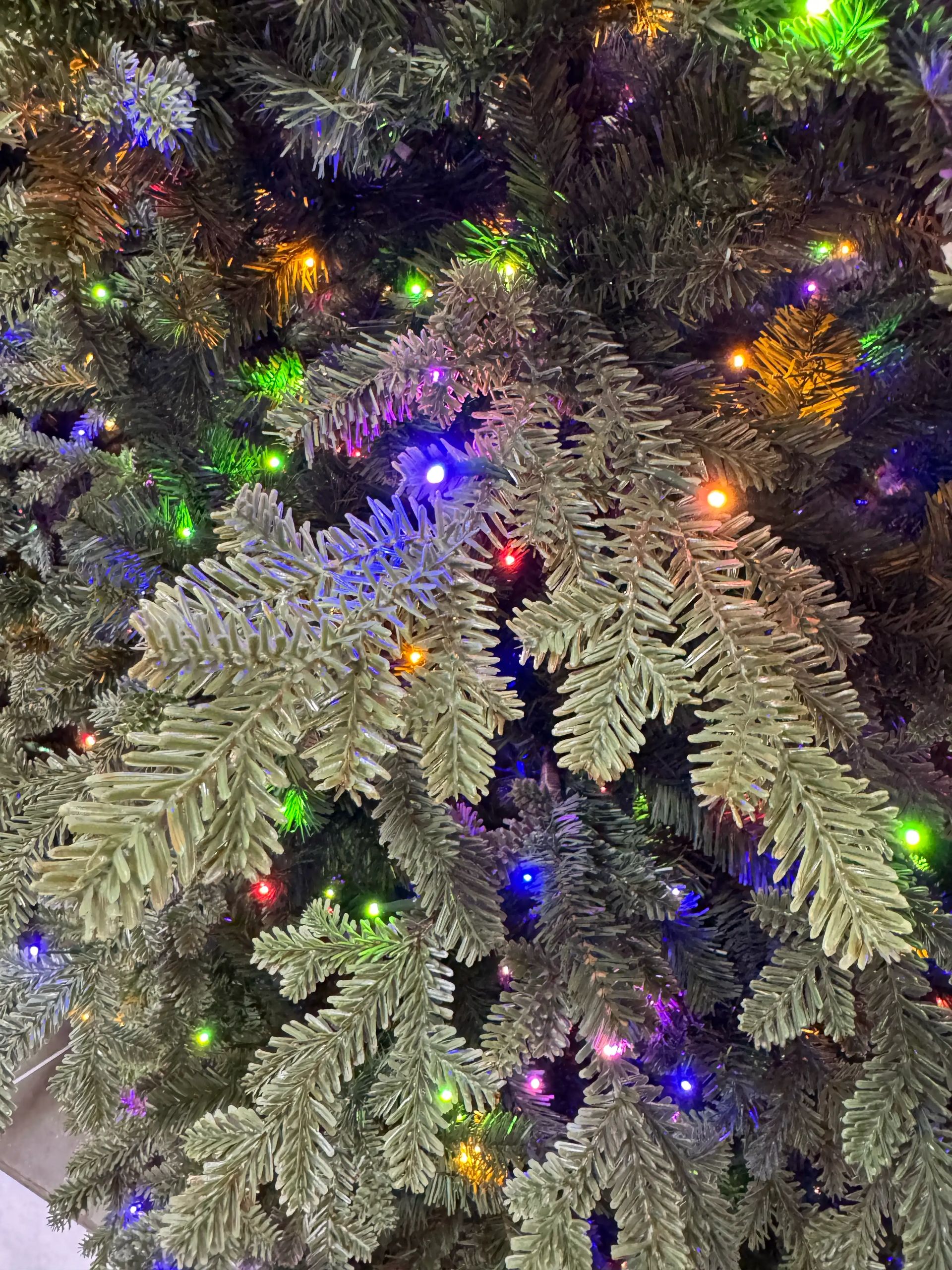 Dense PVC fir needles in sage-gray tone, multicolor micro LED lights (blue, green, orange, red, purple) throughout branches