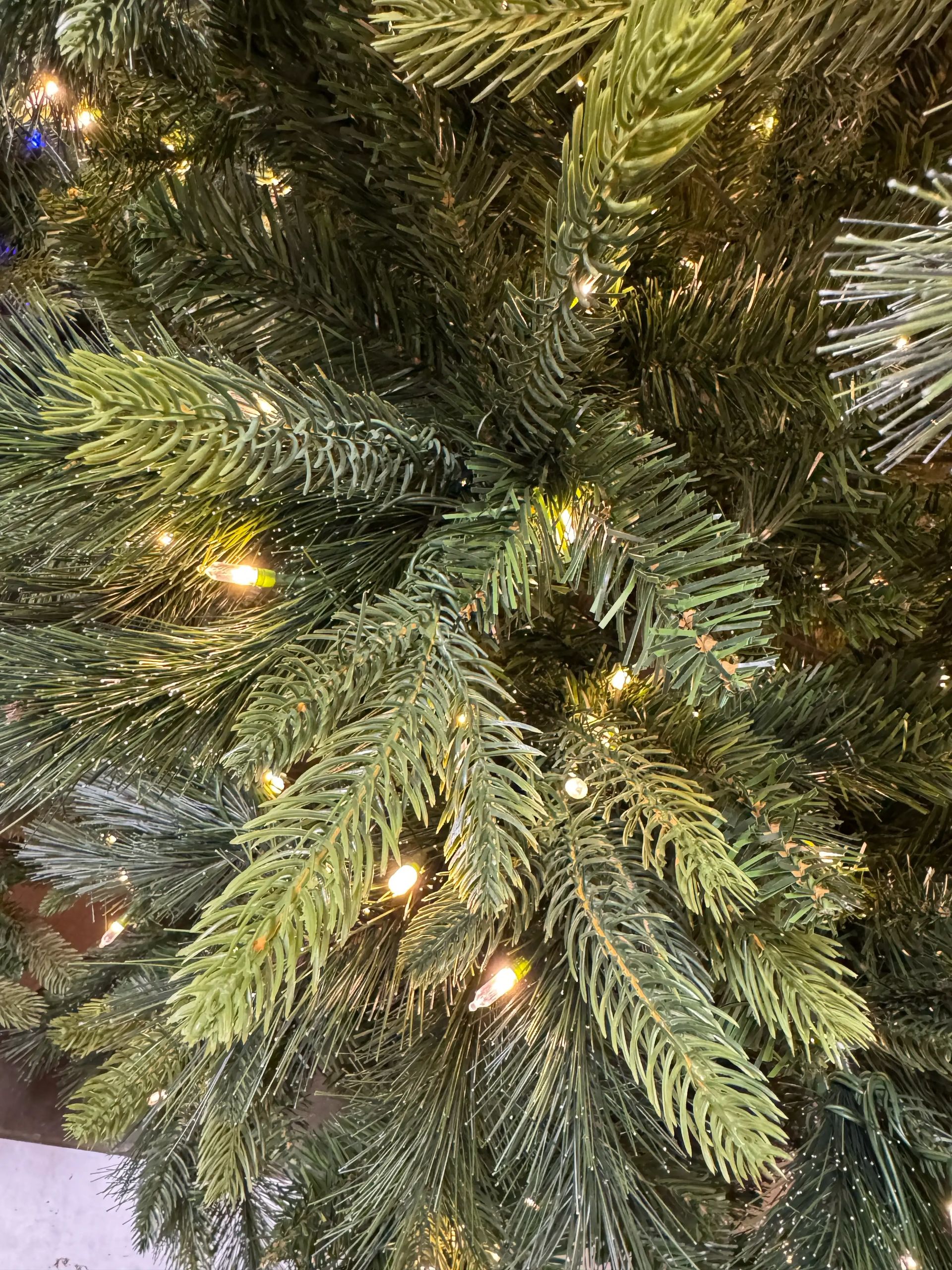 Dense PVC pine needles in green shades with warm white mini LED lights distributed throughout branches