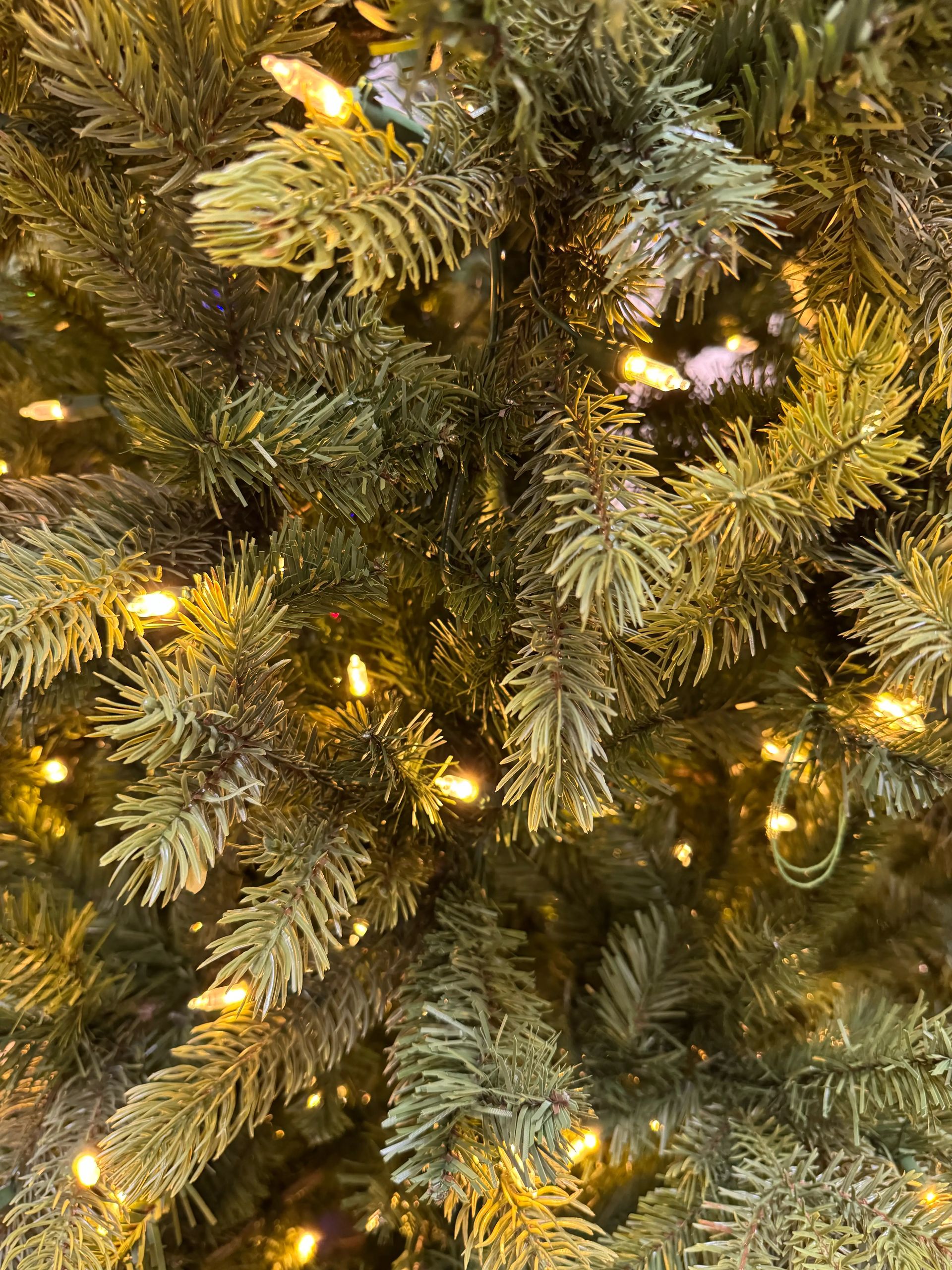 Dense mixed PVC/PE spruce needles in olive-green tones, warm white mini bulbs evenly distributed throughout branches