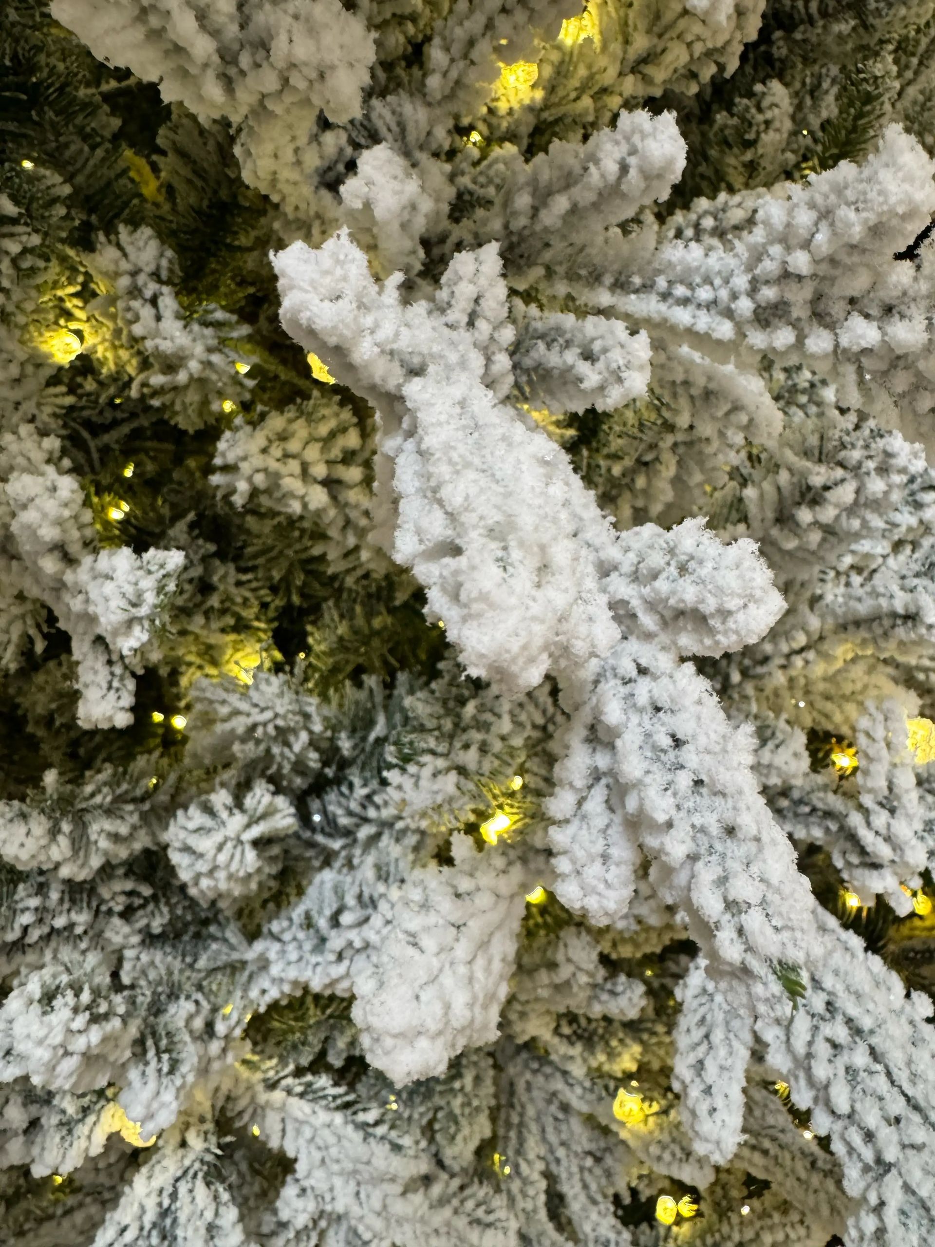 Heavy white flocking on mixed PVC/PE fir branches, warm yellow micro LEDs scattered throughout, dense needle coverage