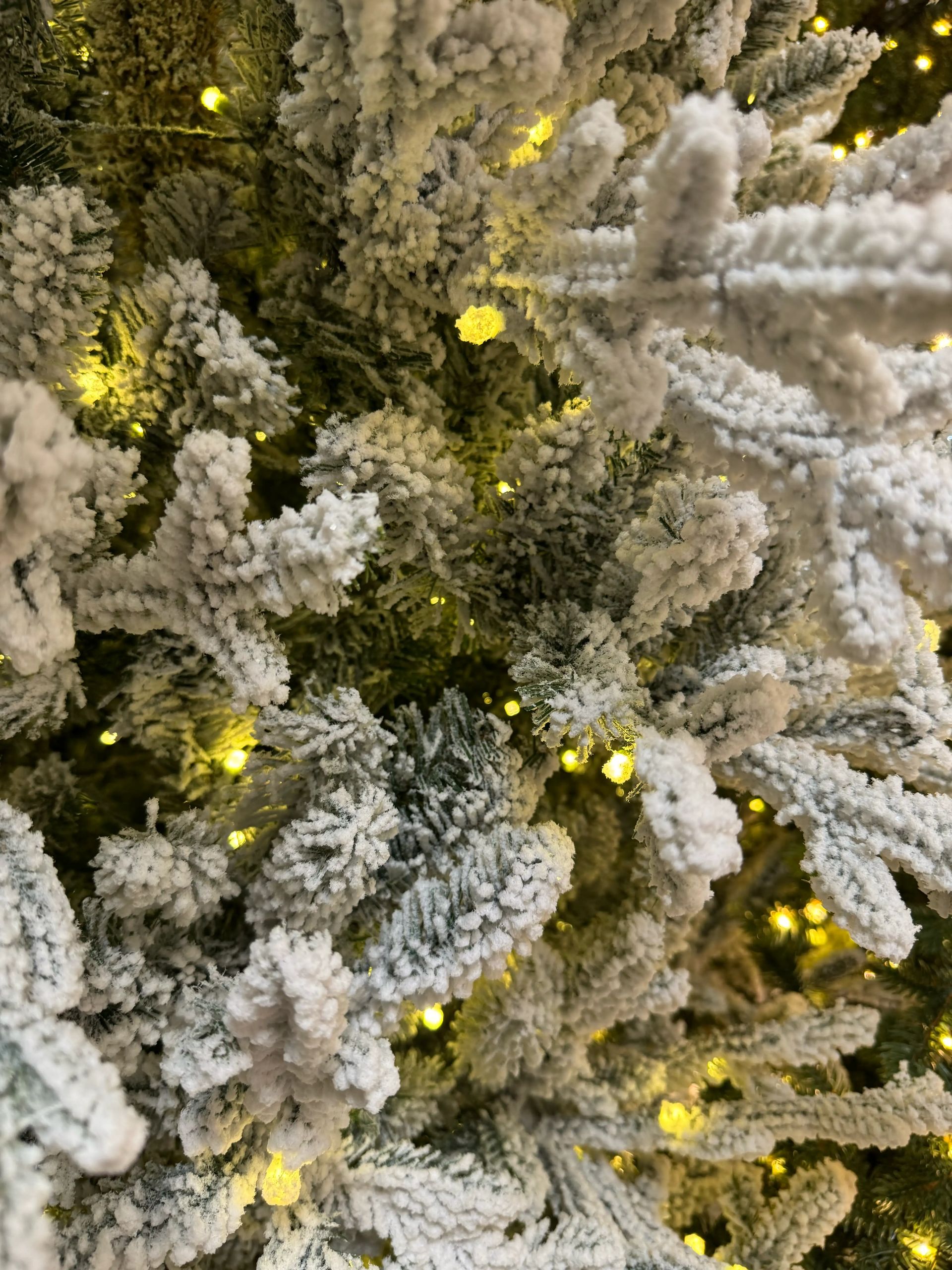 Heavy white flocked fir branches with warm micro LEDs, dense coverage, minimal green showing through flocking