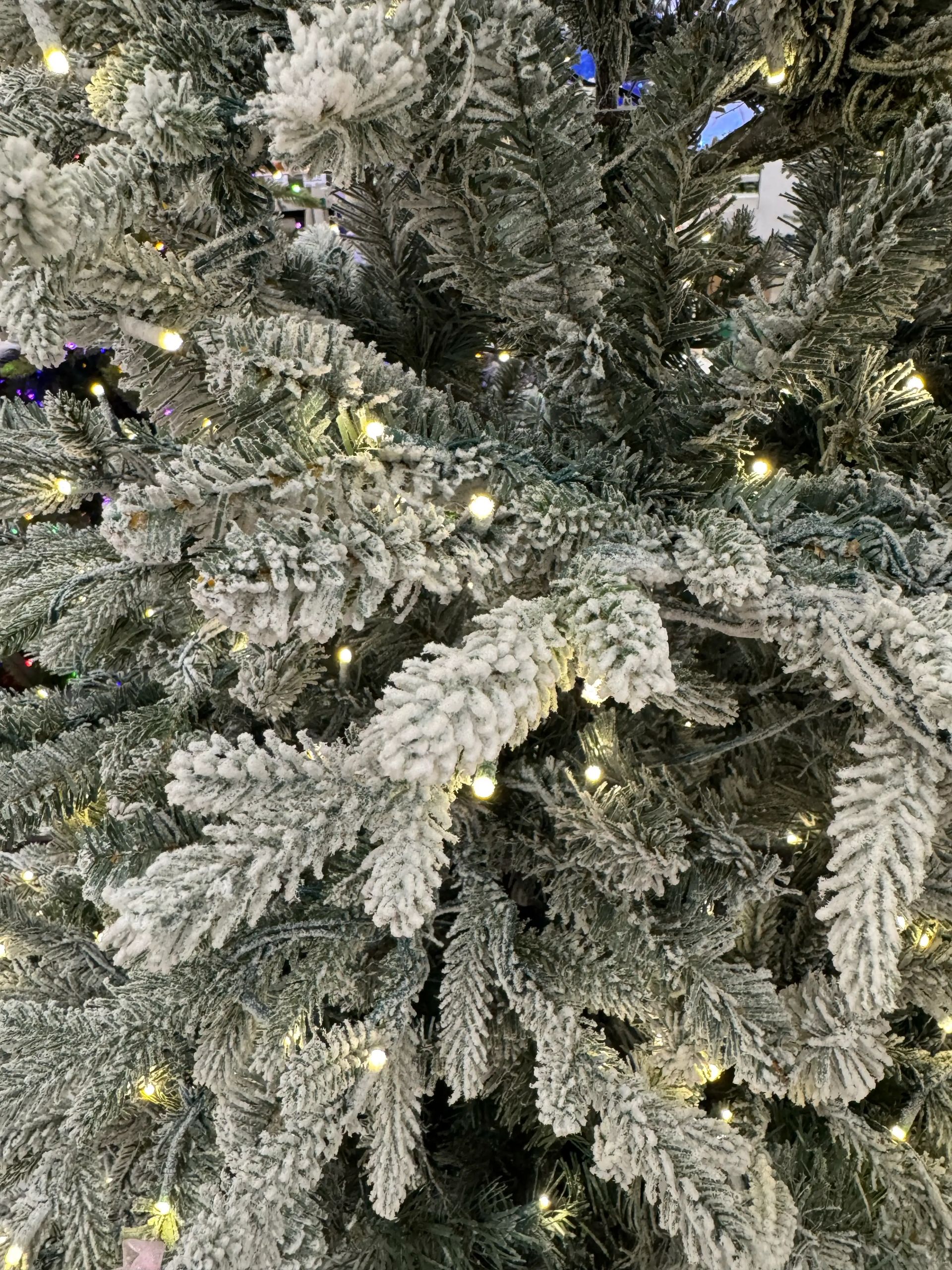 Dense flocked fir branches with heavy white coating, warm white micro LEDs, mixed PVC/PE needles visible throughout