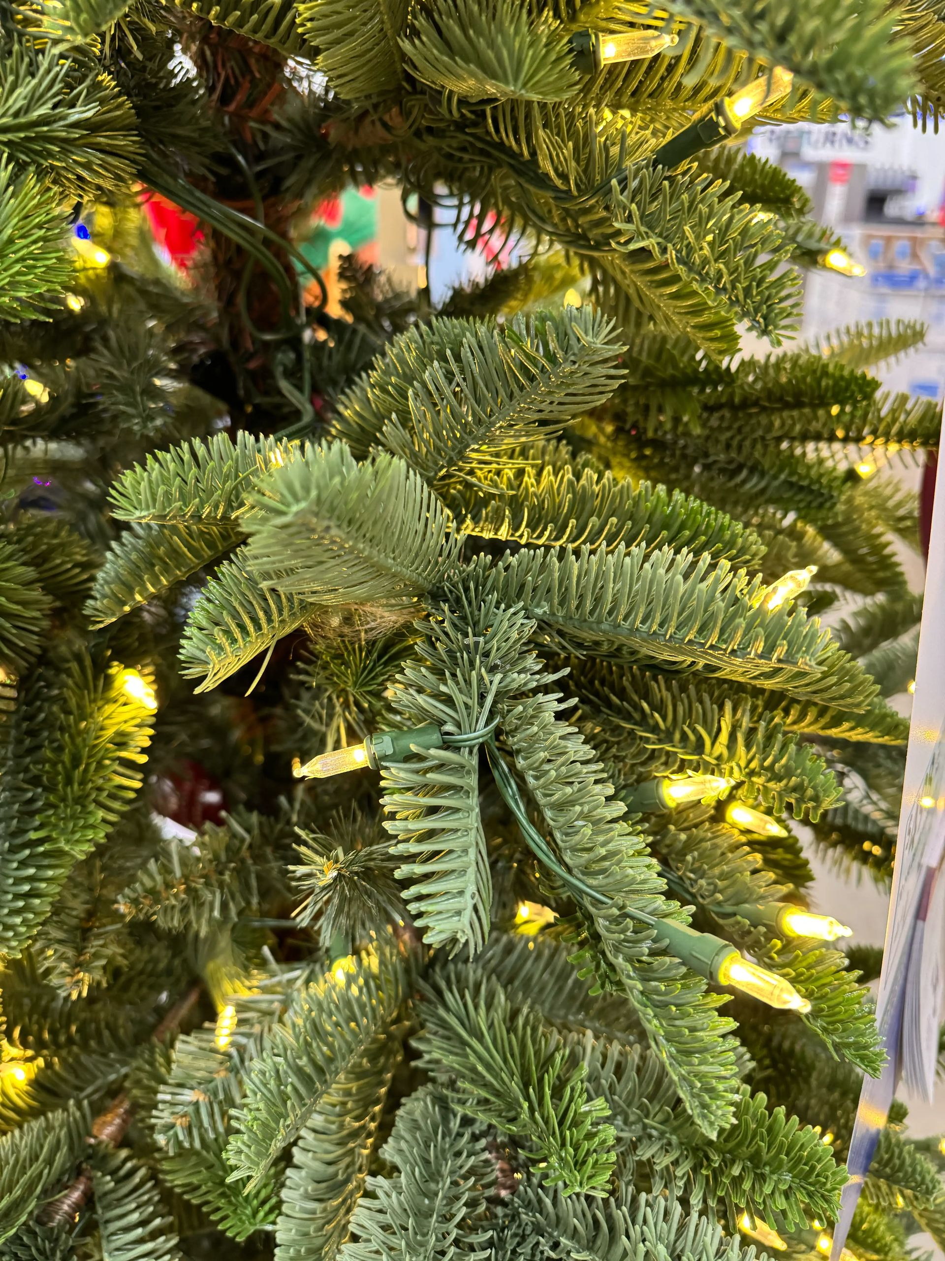 Dense mixed PVC and molded PE fir needles in green tones, warm white mini LED bulbs interspersed throughout branches