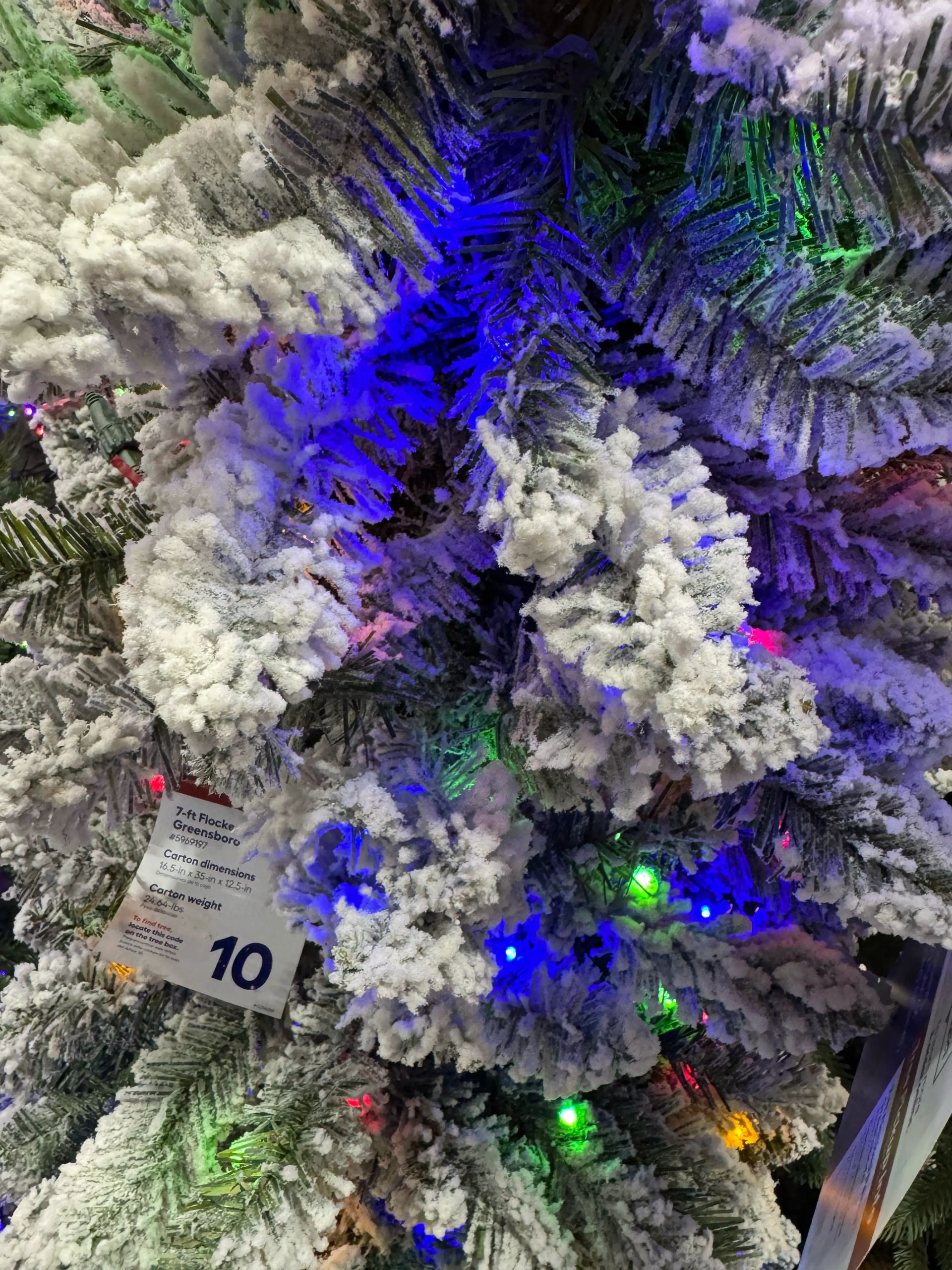 Heavy white flocking on PVC pine branches, multicolor LED lights throughout, dense snow-dusted appearance