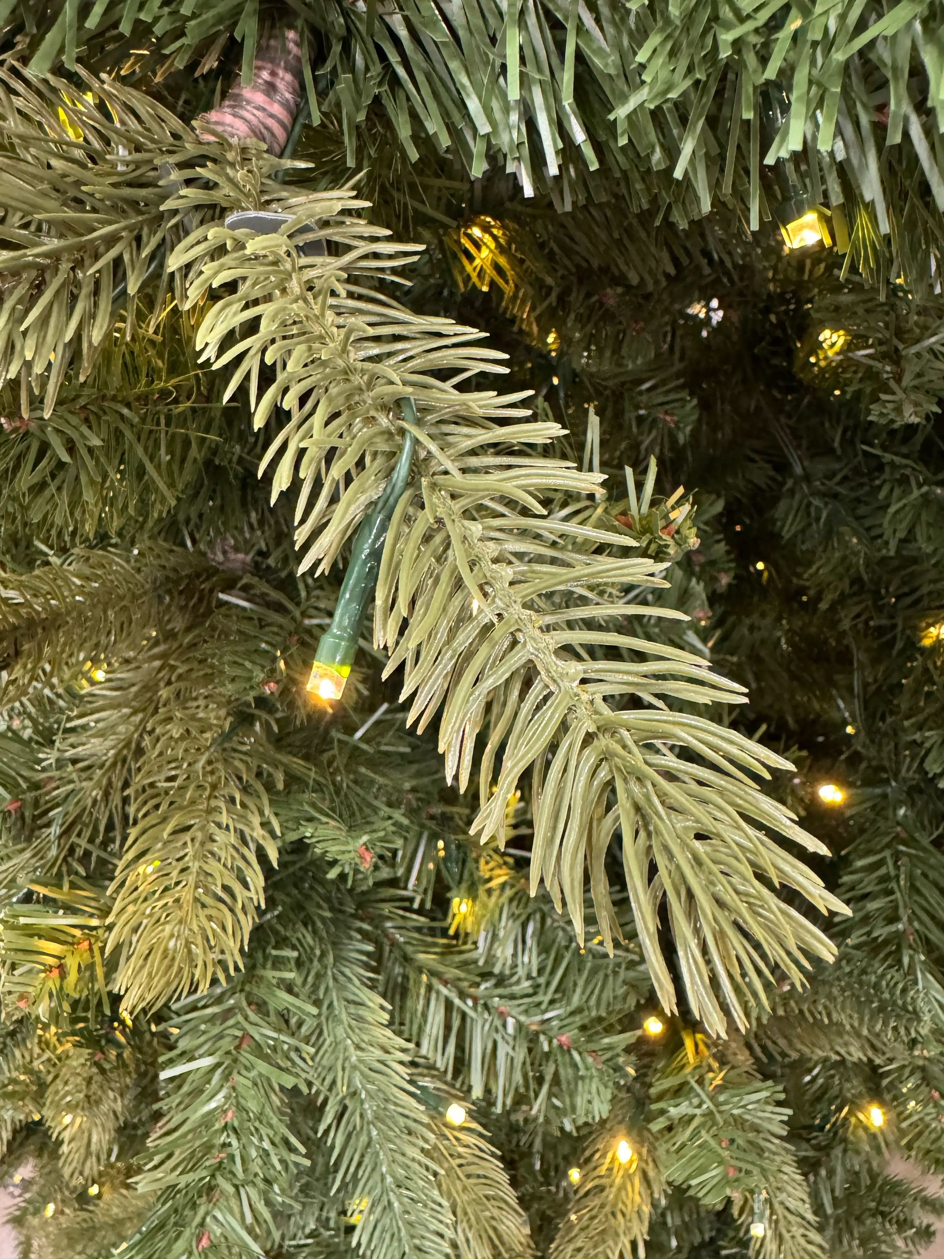Mixed PVC and molded PE fir needles in sage-green tones, warm white micro LEDs scattered throughout branches