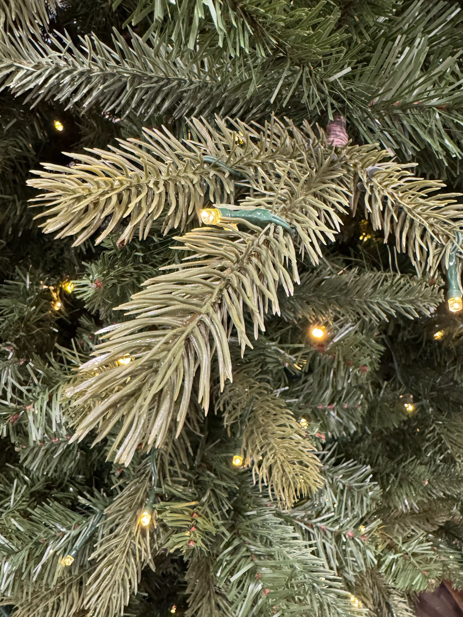 Mixed PVC and molded PE fir needles in frosted tips, warm white mini bulbs, moderate density with some visible gaps