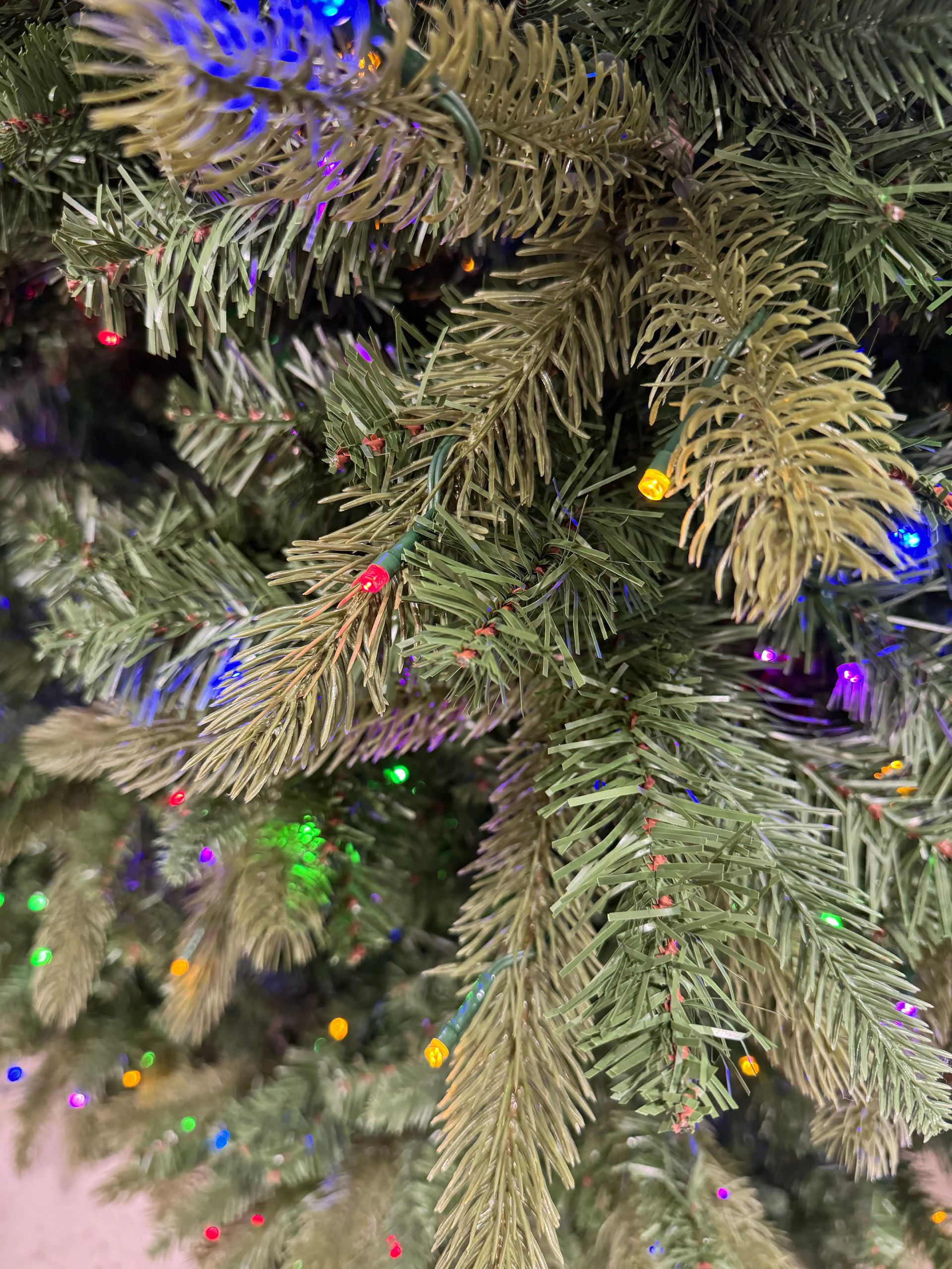 Mixed PVC and molded PE fir needles, multicolor mini bulbs scattered throughout, moderate density with some gaps