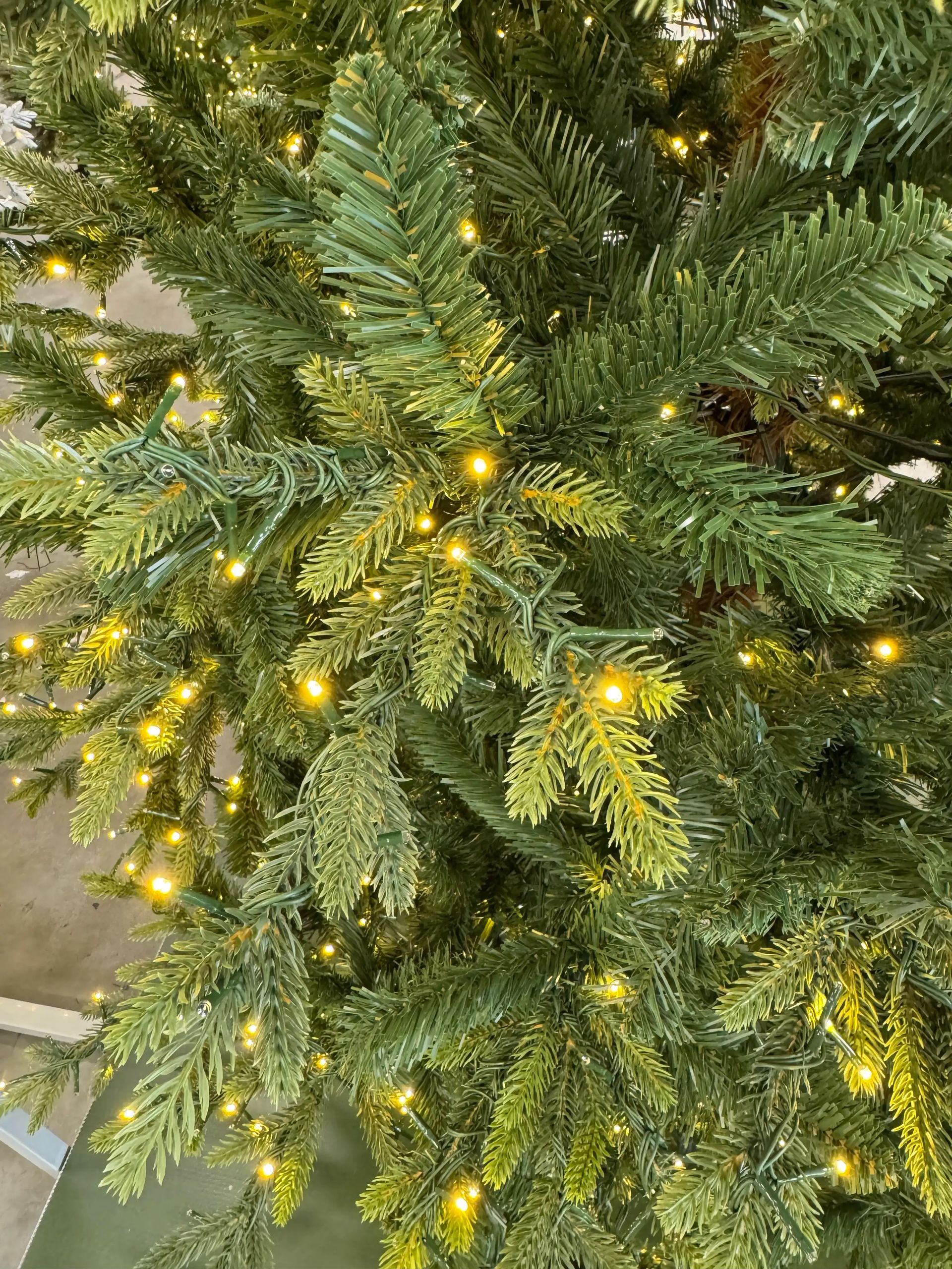 Mixed PVC and molded PE spruce needles in varied green tones, dense warm white LED coverage throughout branches